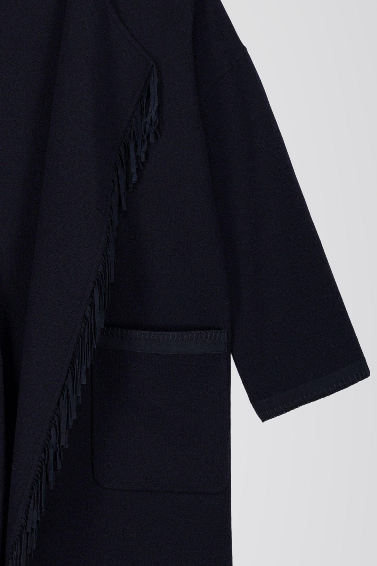 Ce manteau long marine allie une coupe ample et un col drapé fluide, agrémenté de franges en daim pour une silhouette élégante et chic.