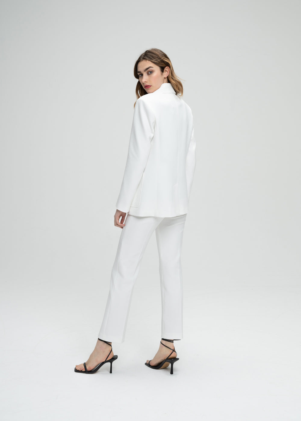 Veste tailleur cintrée blanc avec poches plaquées, col tailleur et détail monogramme manche