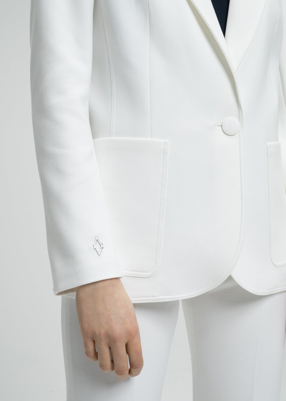 Veste tailleur cintrée blanc avec poches plaquées, col tailleur et détail monogramme manche