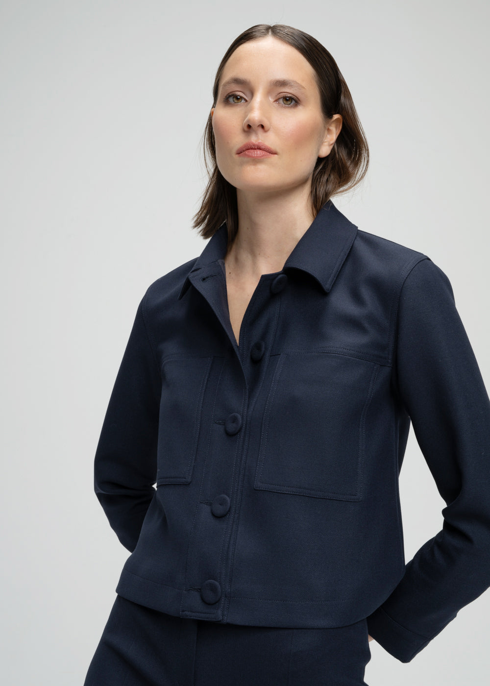 Veste courte marine avec poches plaquées boutons apparents et détails œillets métalliques manches