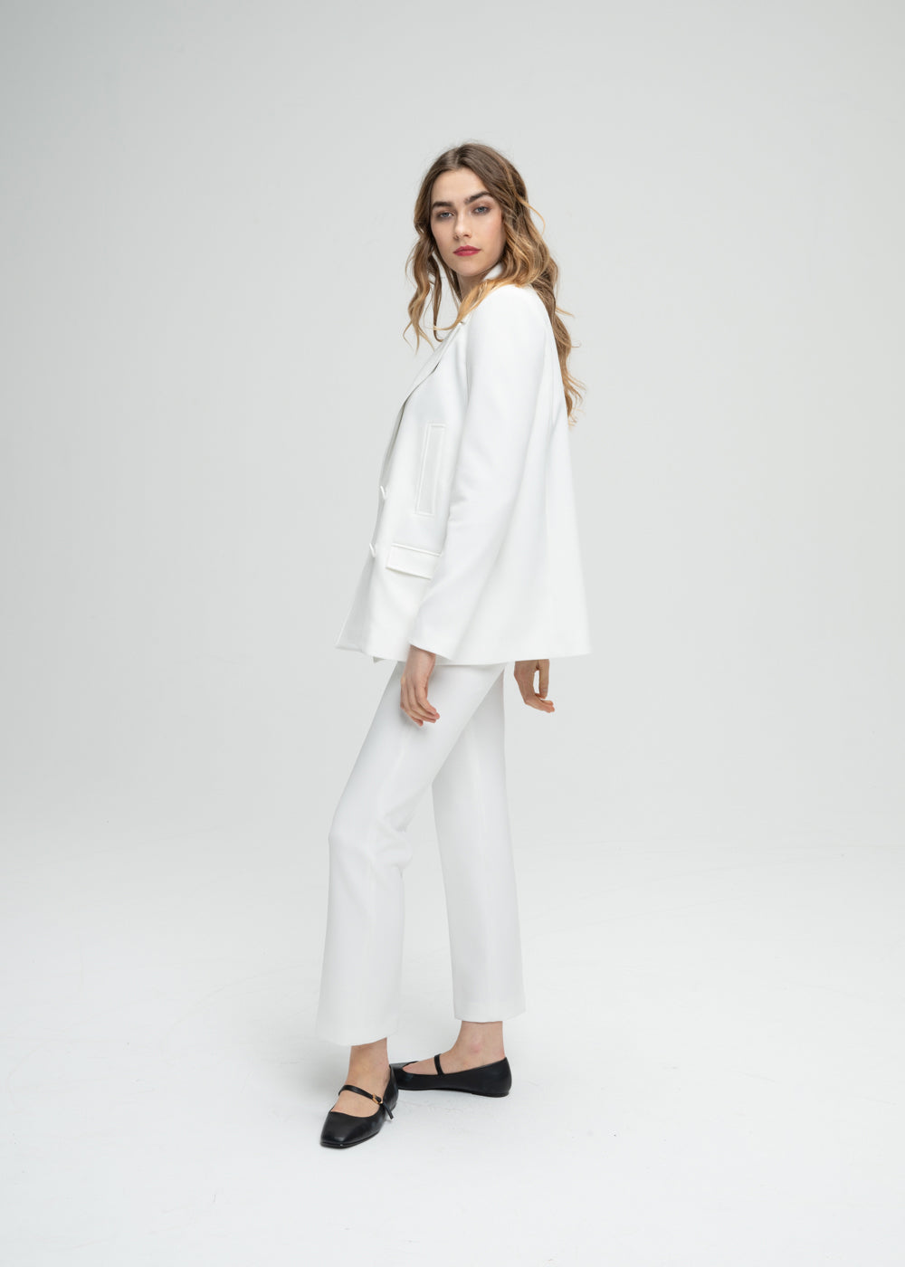 Modèle portant un manteau caban blanc à coupe droite pour une allure subtilement surdimensionnée. Doté d’un double boutonnage croisé, de poches passepoilées et de poches à rabat fonctionnelles. Le logo sur chaque élément ajoute une touche personnalisée et raffinée à ce modèle élégant.