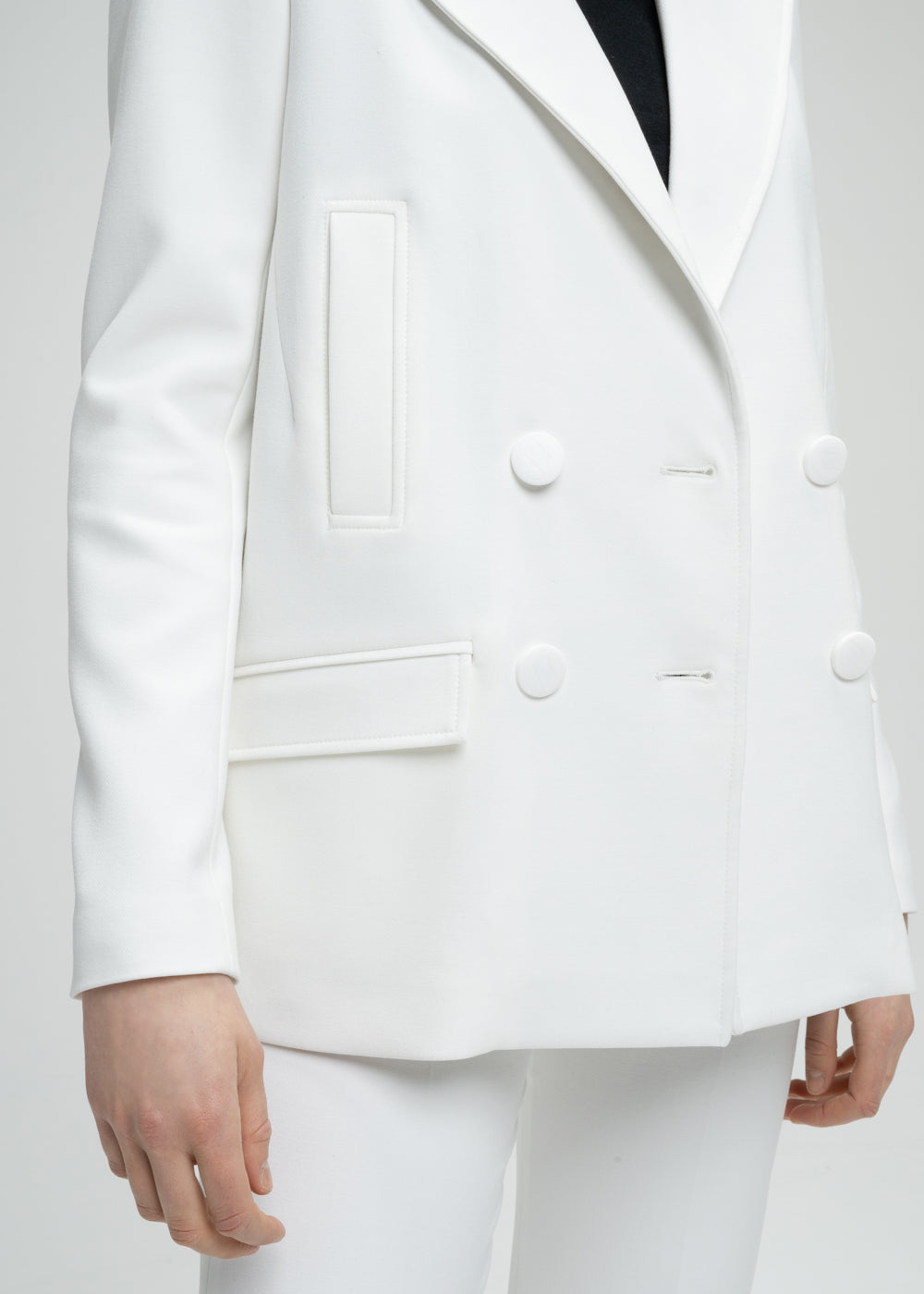 Gros plan un manteau caban blanc à coupe droite pour une allure subtilement surdimensionnée. Doté d’un double boutonnage croisé, de poches passepoilées et de poches à rabat fonctionnelles. Le logo sur chaque élément ajoute une touche personnalisée et raffinée à ce modèle élégant.