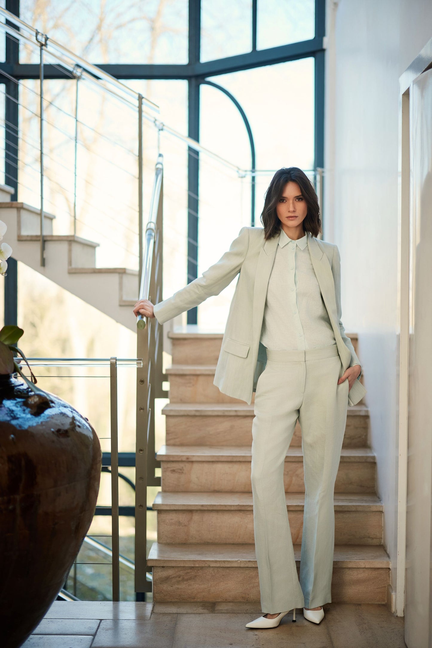 Une veste tailleur vert d'eau en lin-viscose, qui offre une coupe raffinée, des boutons assortis et des poches passepoil pour un look élégant et pratique.