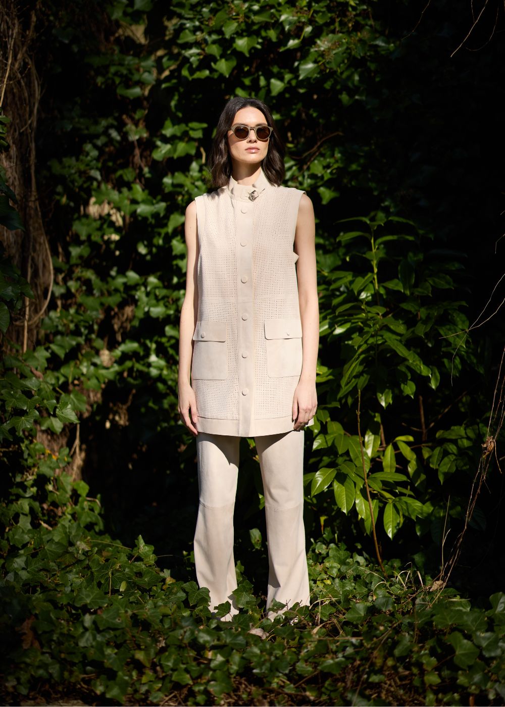 Veste sans manches en daim perforé beige clair et pantalon droit assorti.