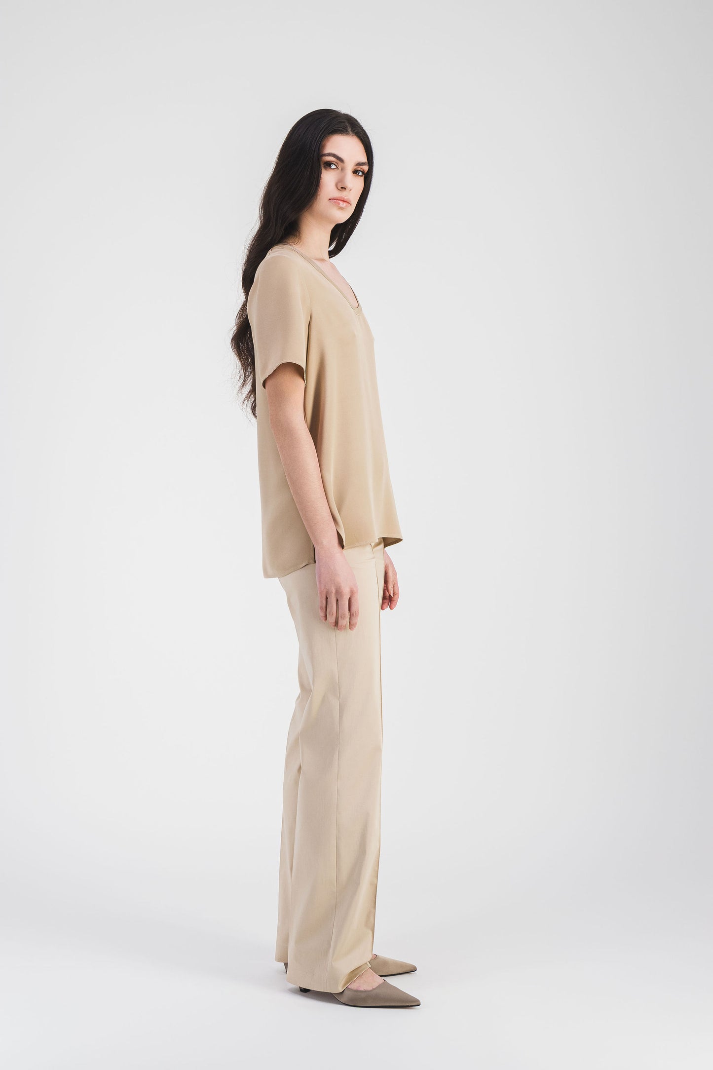 Vue de côté de la blouse beige en soie, mettant en valeur son col rond et ses finitions parfaites.
