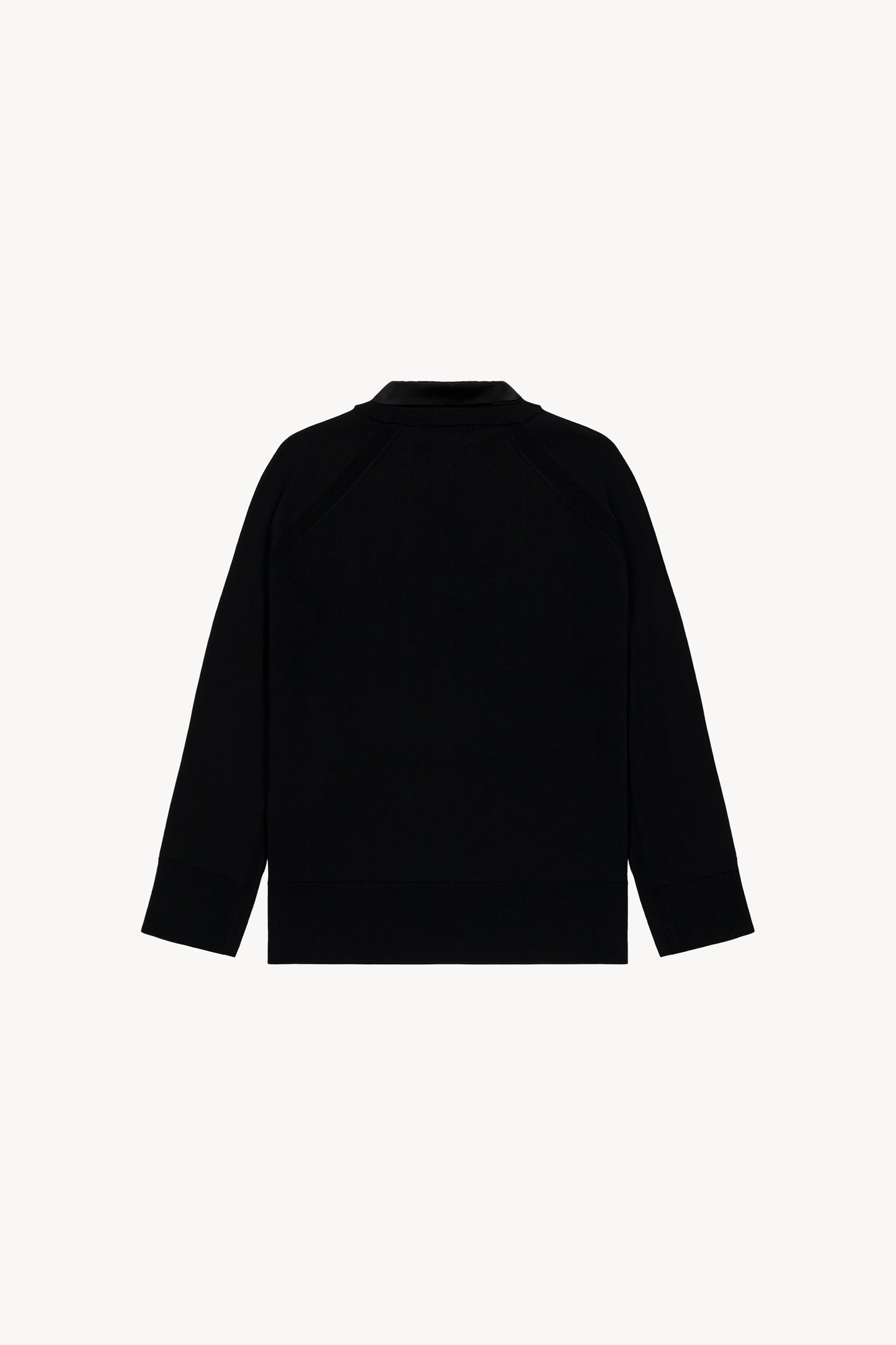 Pull noir en laine et satin de soie, col chemise ouvert et détails satinés aux poignets.