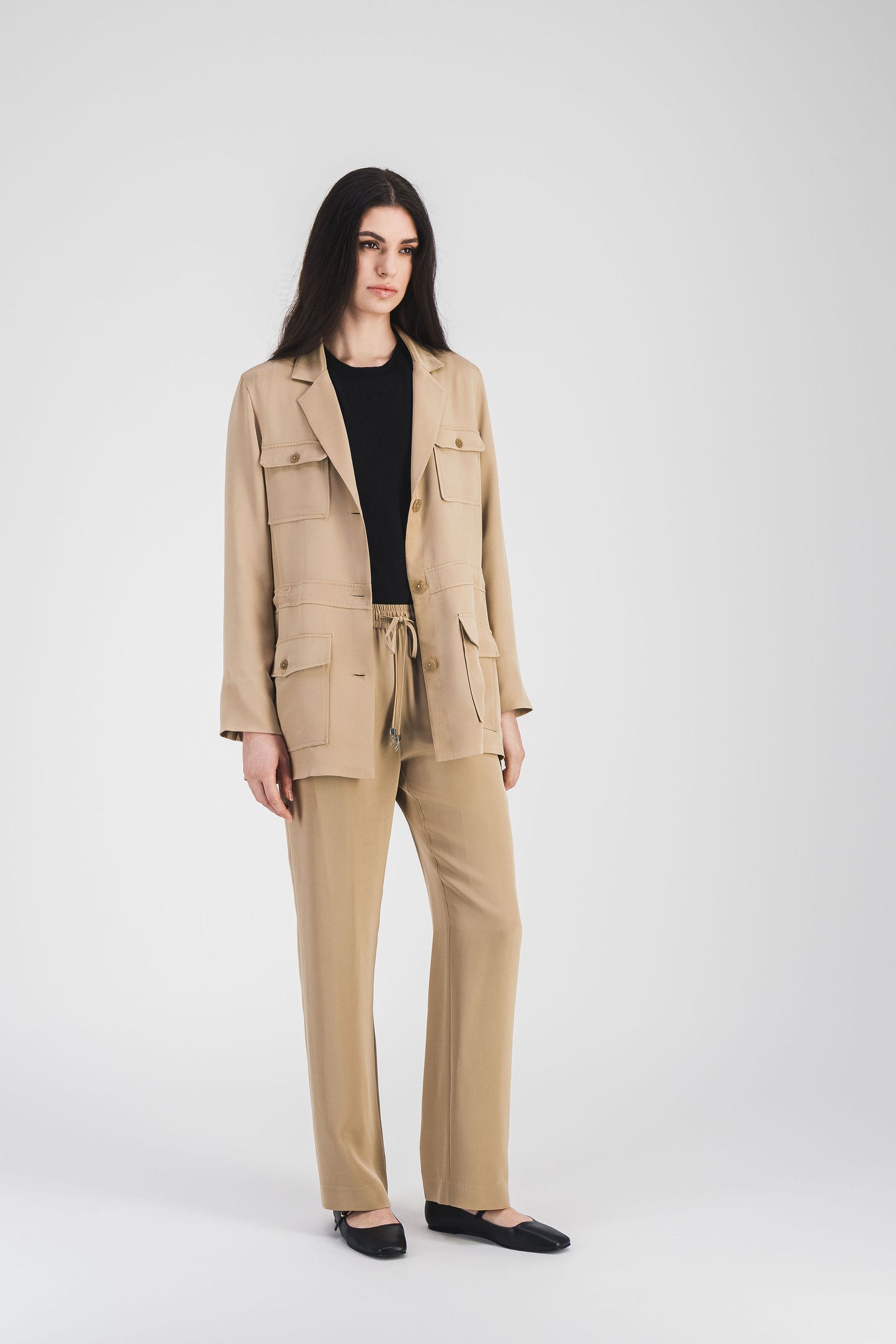 Veste Apostrophe en soie beige avec cordon ajustable, embouts métalliques gravés, col tailleur et boutons ton sur ton pour une touche élégante.