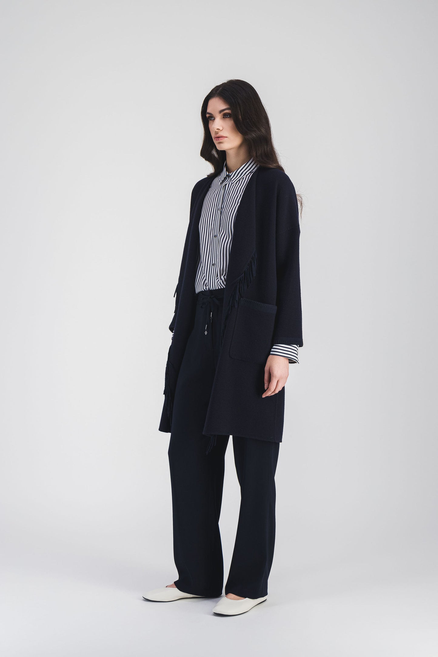 Manteau en double face crêpe avec franges en daim, coupe structurée mi-cuisse, idéal pour un look moderne et sophistiqué.