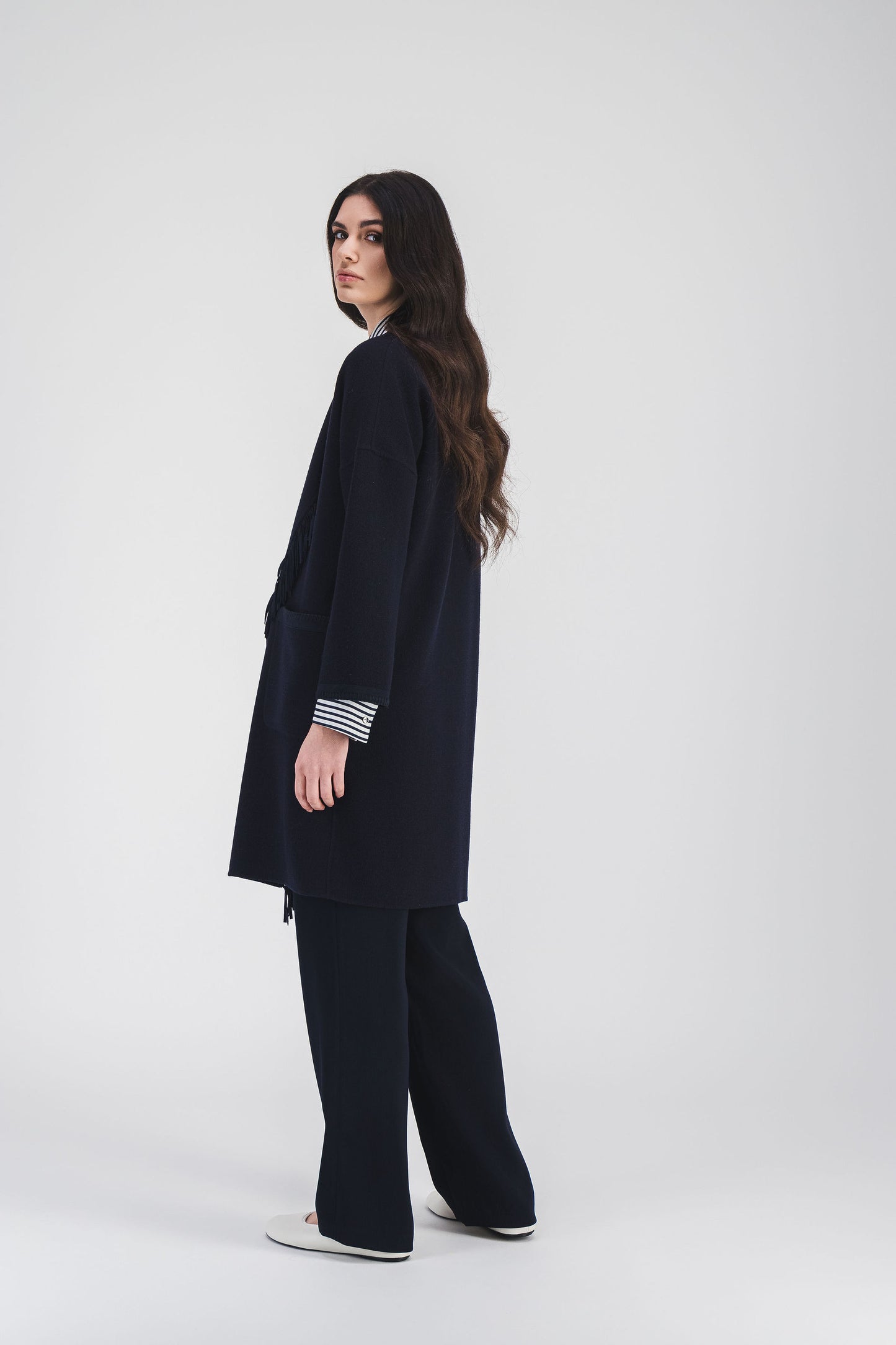 Manteau ample en crêpe double face avec franges en daim et coupe mi-cuisse, une pièce audacieuse.