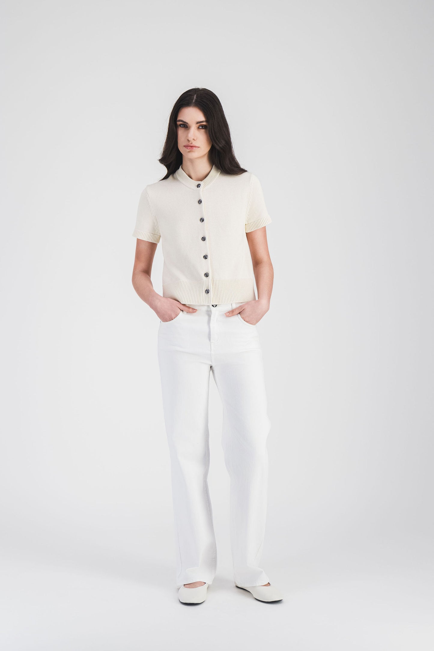 Gilet blanc cassé à manches courtes et finitions côtelées, orné de boutons en métal, pour un look élégant et minimaliste.