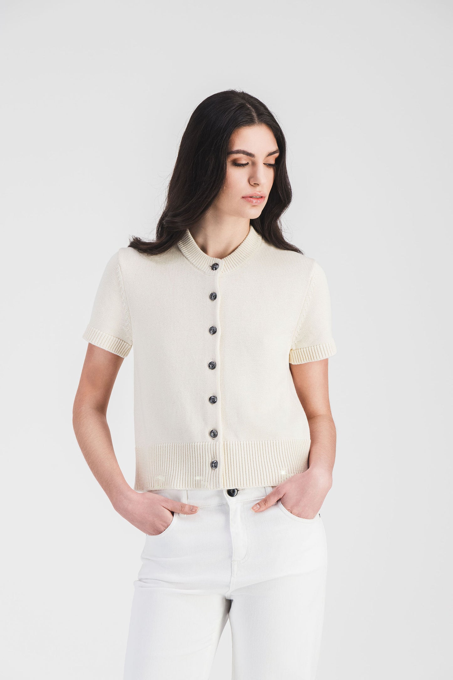 Gilet blanc cassé à boutons en métal et finitions côtelées, un choix élégant pour une silhouette légère et raffinée.