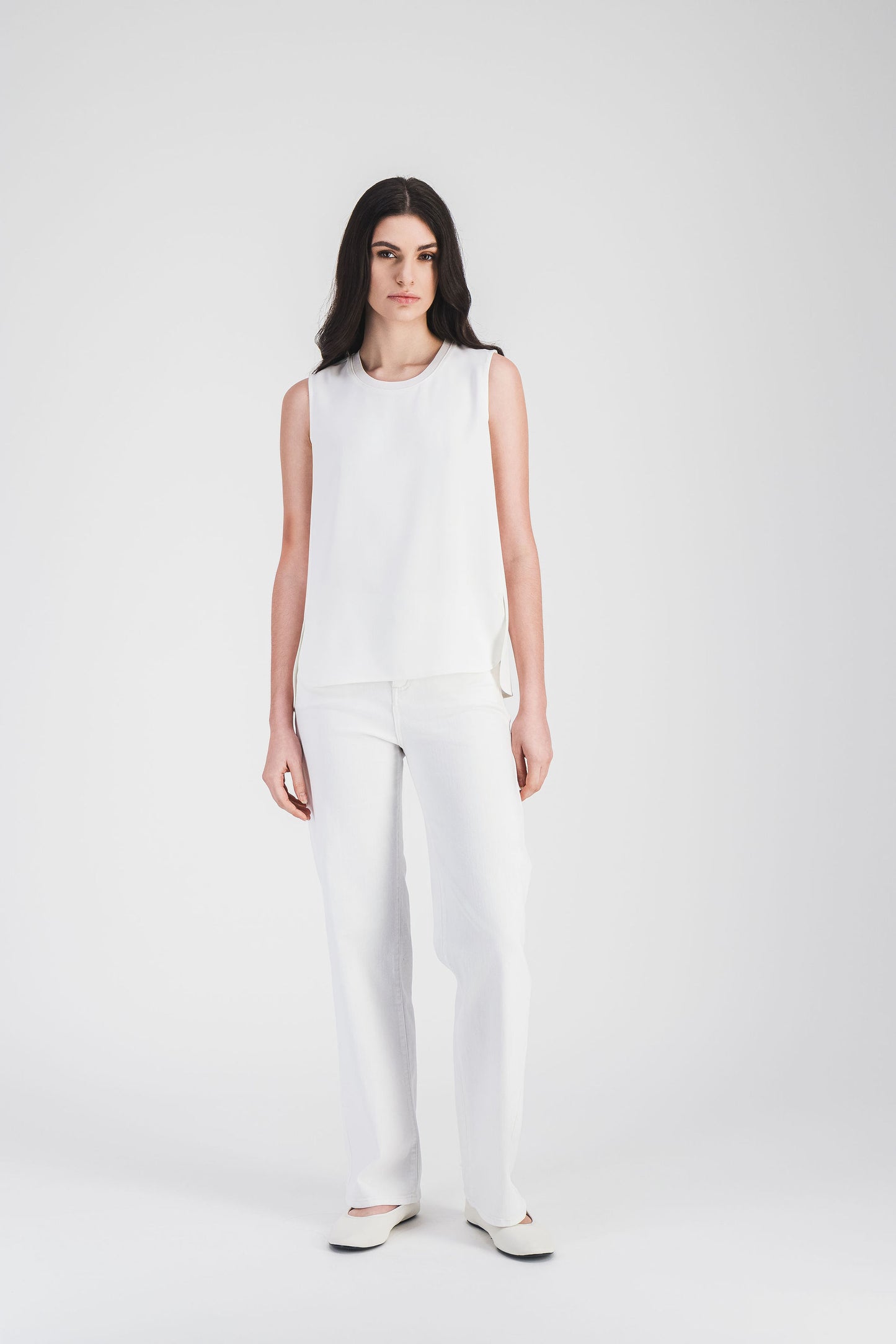 Ce top sans manches blanc cassé avec un col en maille côtelée et coutures discrètes dégage un style moderne