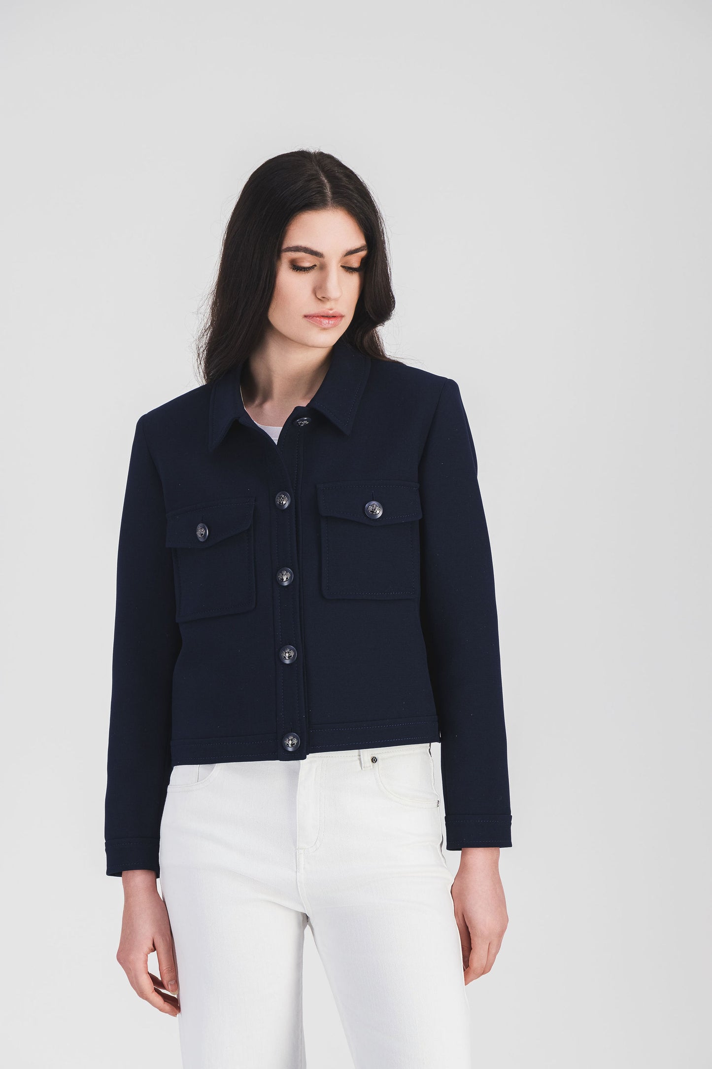 Élégante veste marine avec col chemise, poches plaquées et bouton militaire.