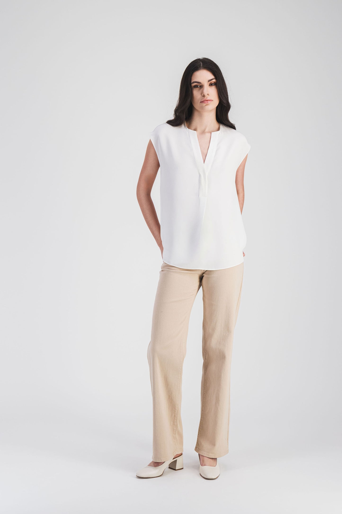 Blouse élégante en soie lourde (crêpe de chine), sans manches, avec une encolure en V et un ourlet légèrement arrondi .