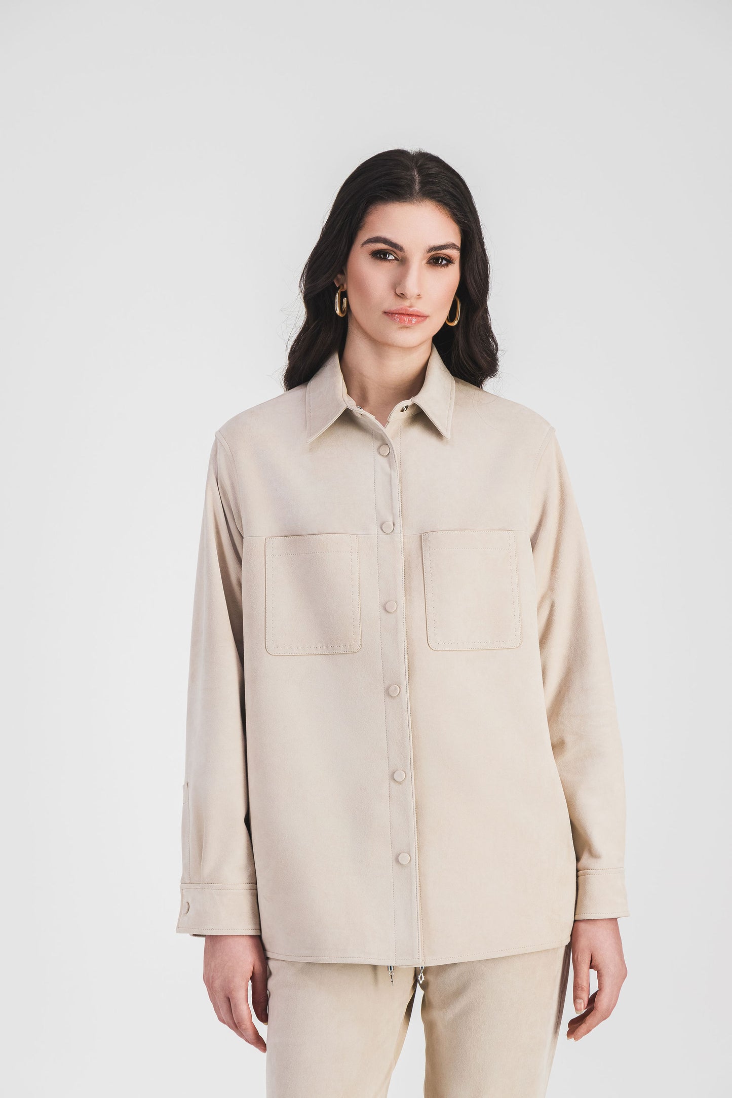 Surchemise beige clair en daim avec poches et surpiqûres, pour un look structuré et raffiné, à porter ouverte ou fermée.