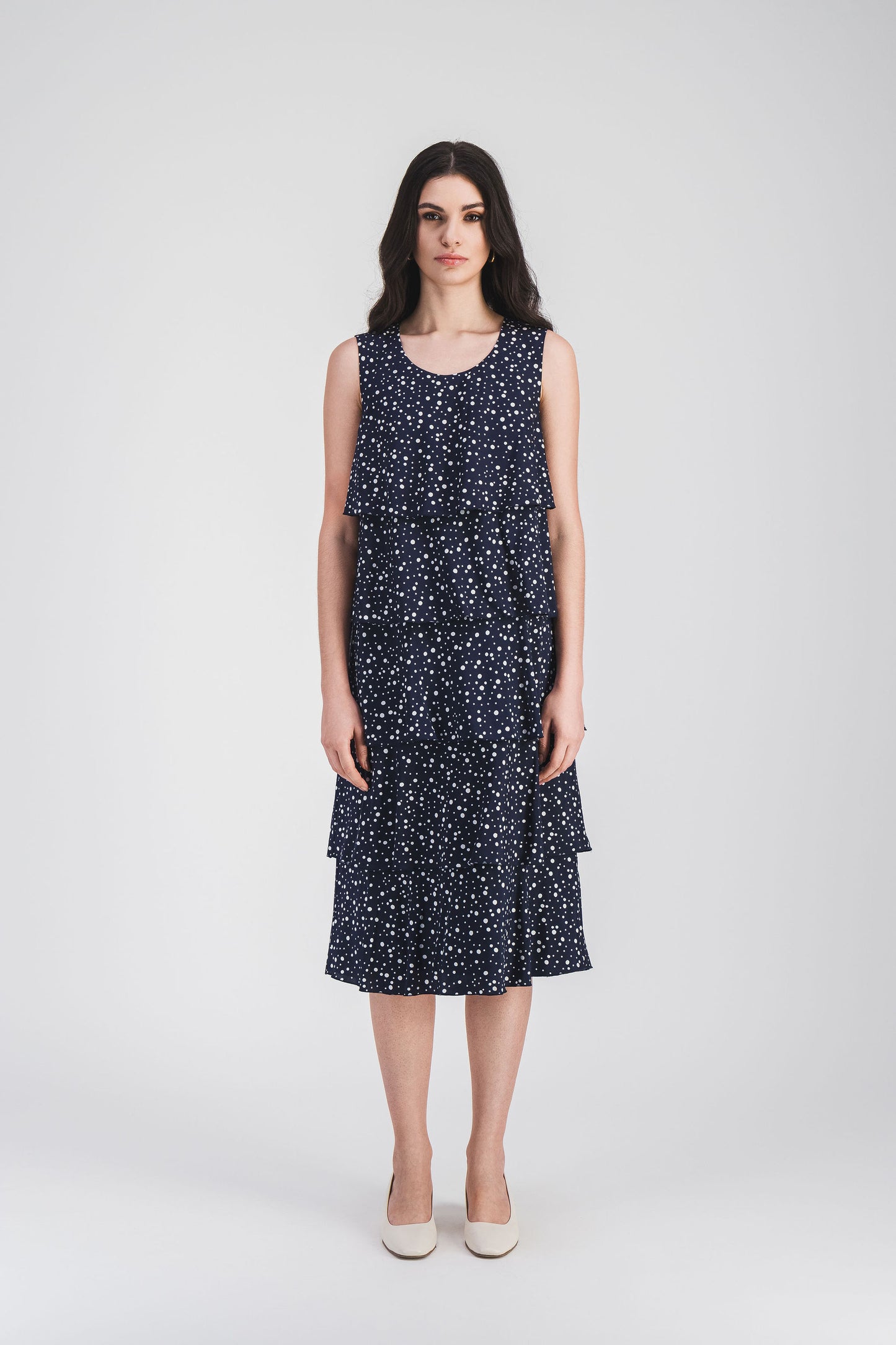 Élégante robe marine à pois avec volants superposés et encolure ronde, offrant une silhouette fluide et un charme intemporel.
