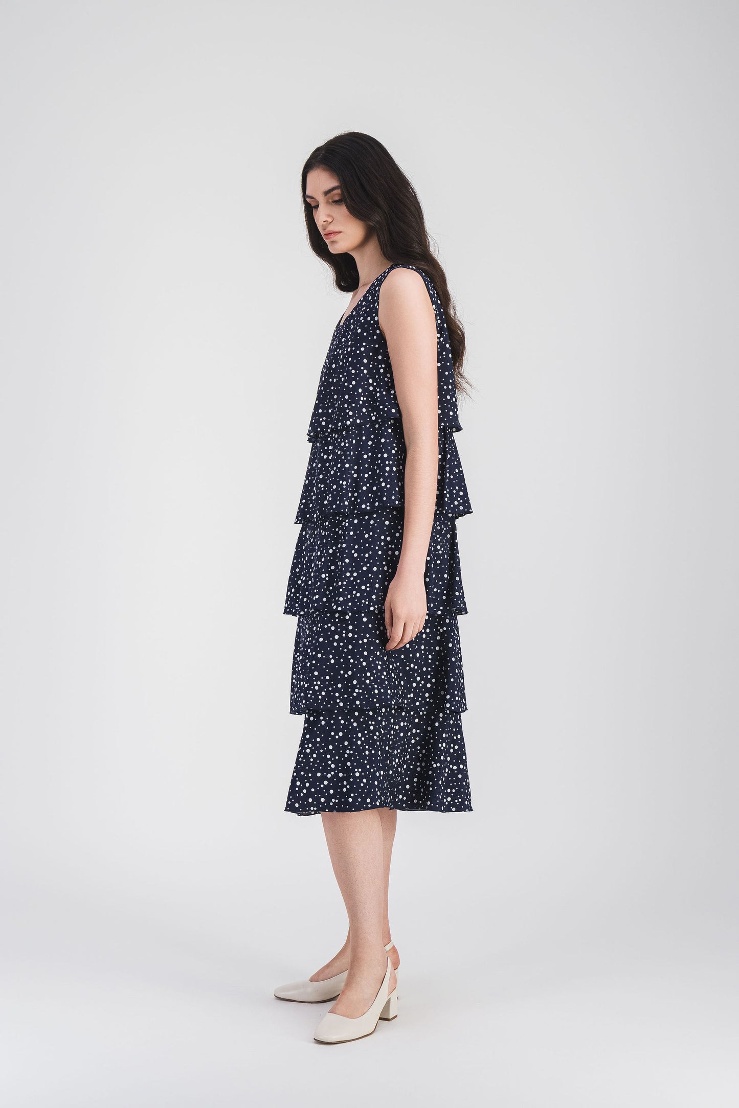 Robe élégante à pois marine, coupe fluide, volants superposés et bouton au dos pour une silhouette chic et intemporelle.