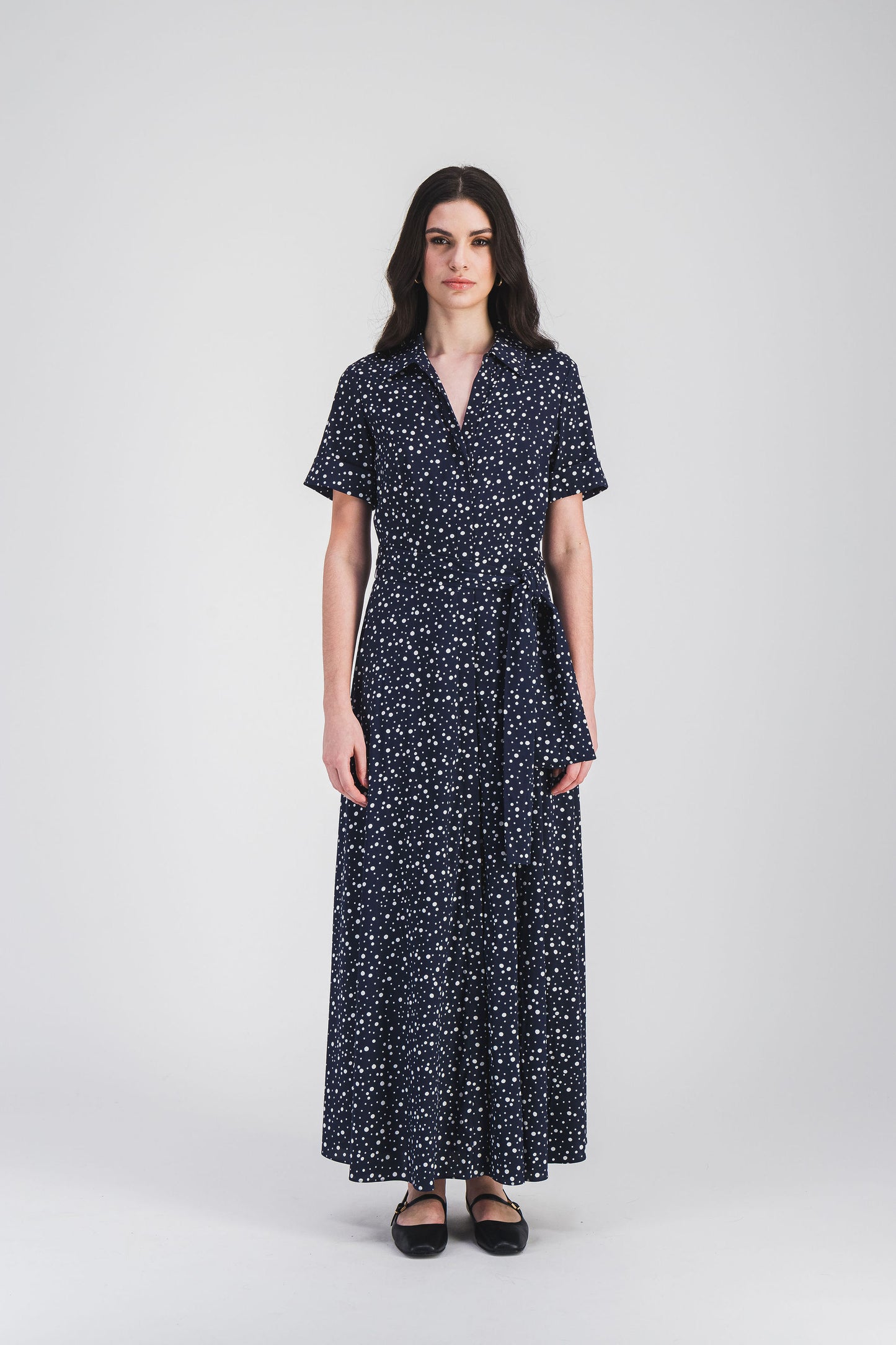 Robe chemise à pois marine, col chemise et ceinture ajustable, alliant confort et style pour une silhouette moderne et élégante.