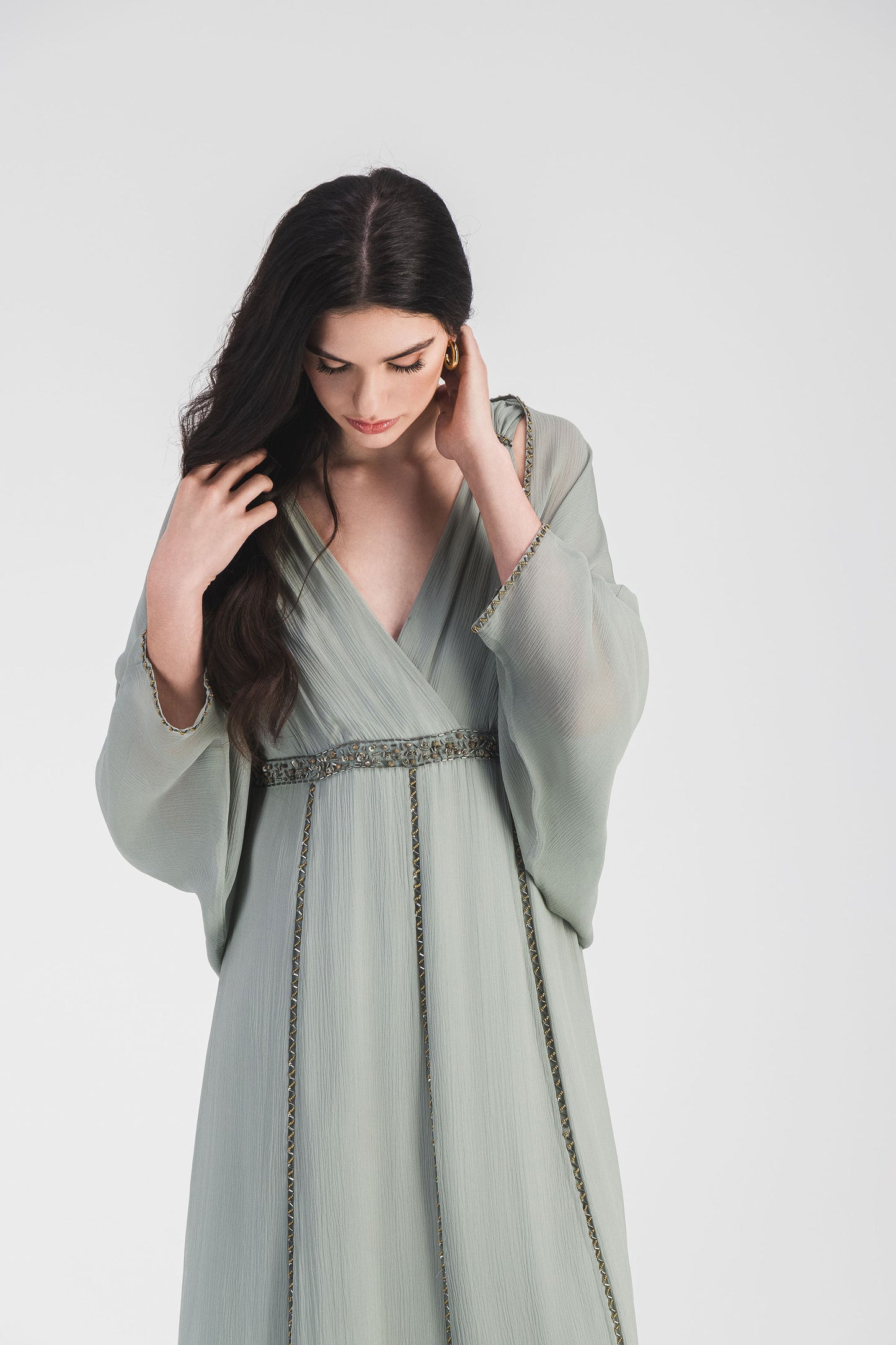 Robe sauge à taille empire, décolleté en V et broderie ton sur ton, créant une silhouette gracieuse et délicatement raffinée.