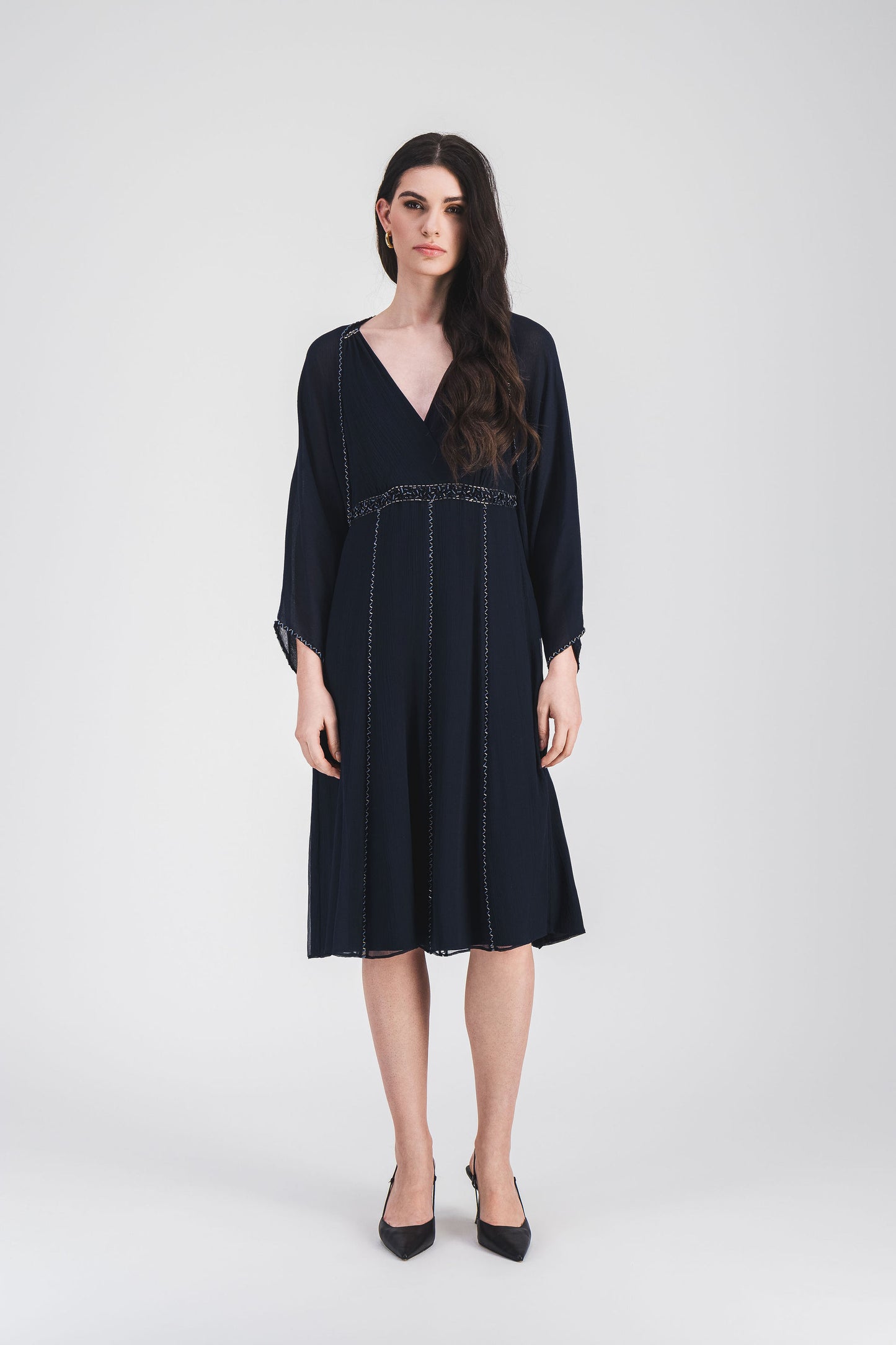 Robe marine à taille empire, décolleté en V et broderie ton sur ton, créant une silhouette gracieuse et délicatement raffinée.