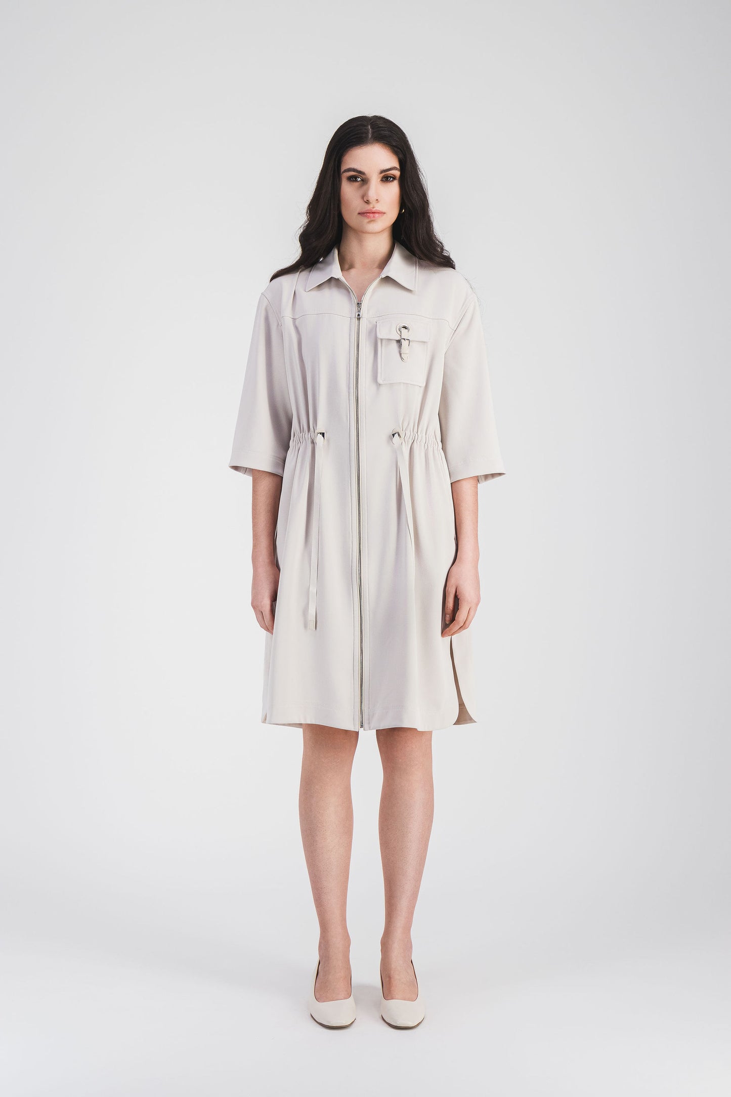 Robe courte en teinte béton , avec poche plaqué décorée d'une boucle métallique apporte une touche d'élégance.