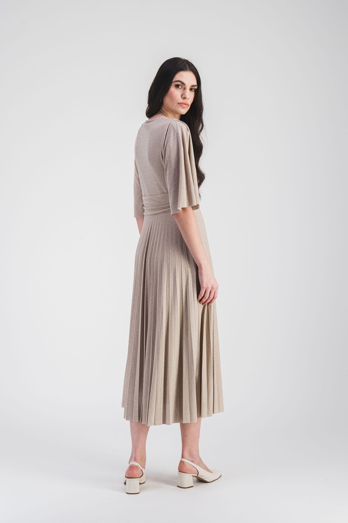 Robe longue cintrée avec col V, manches volantées et tissu scintillant. Le plissé soleil crée une silhouette fluide et pleine de grâce.