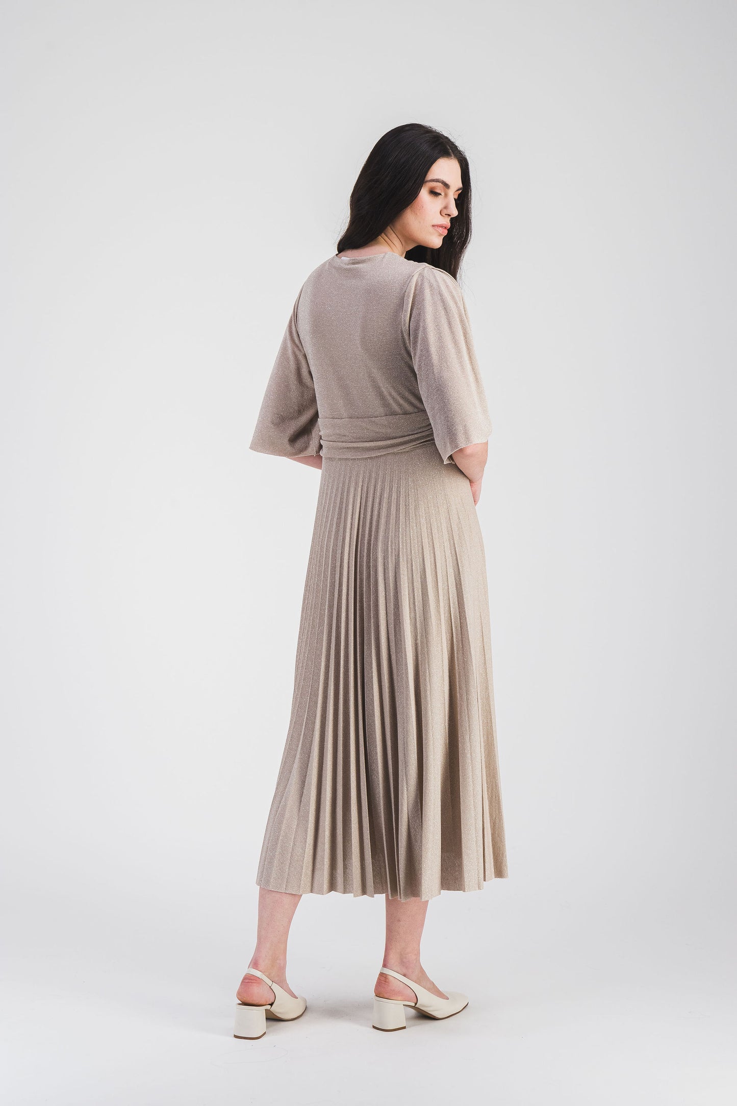 Élégante, cette robe longue cintrée à manches volantées, col V et tissu scintillant se distingue par son plissé soleil fluide et raffiné.