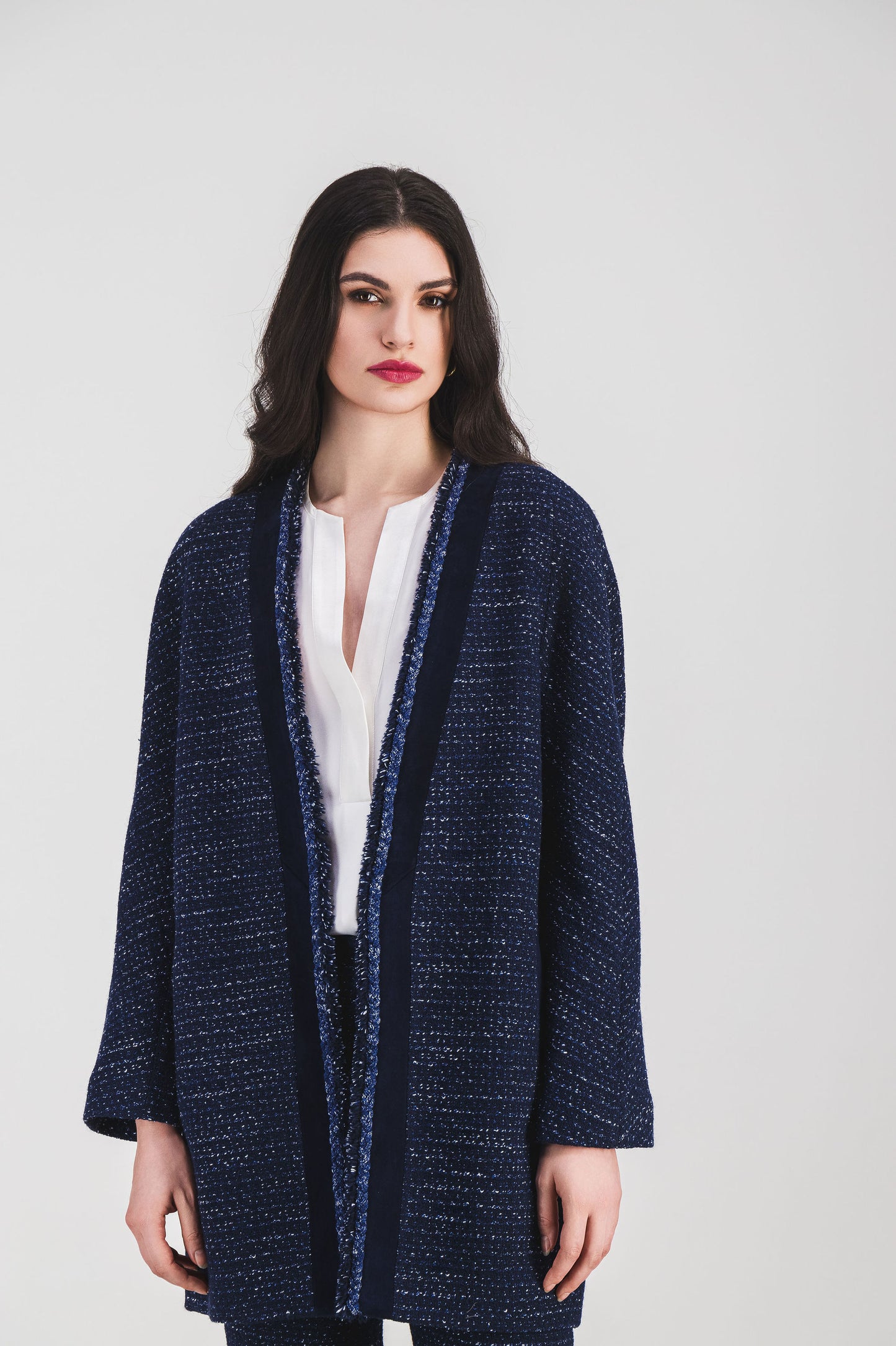 Détail raffiné : manteau fluide marine orné de franges et de touches en daim.