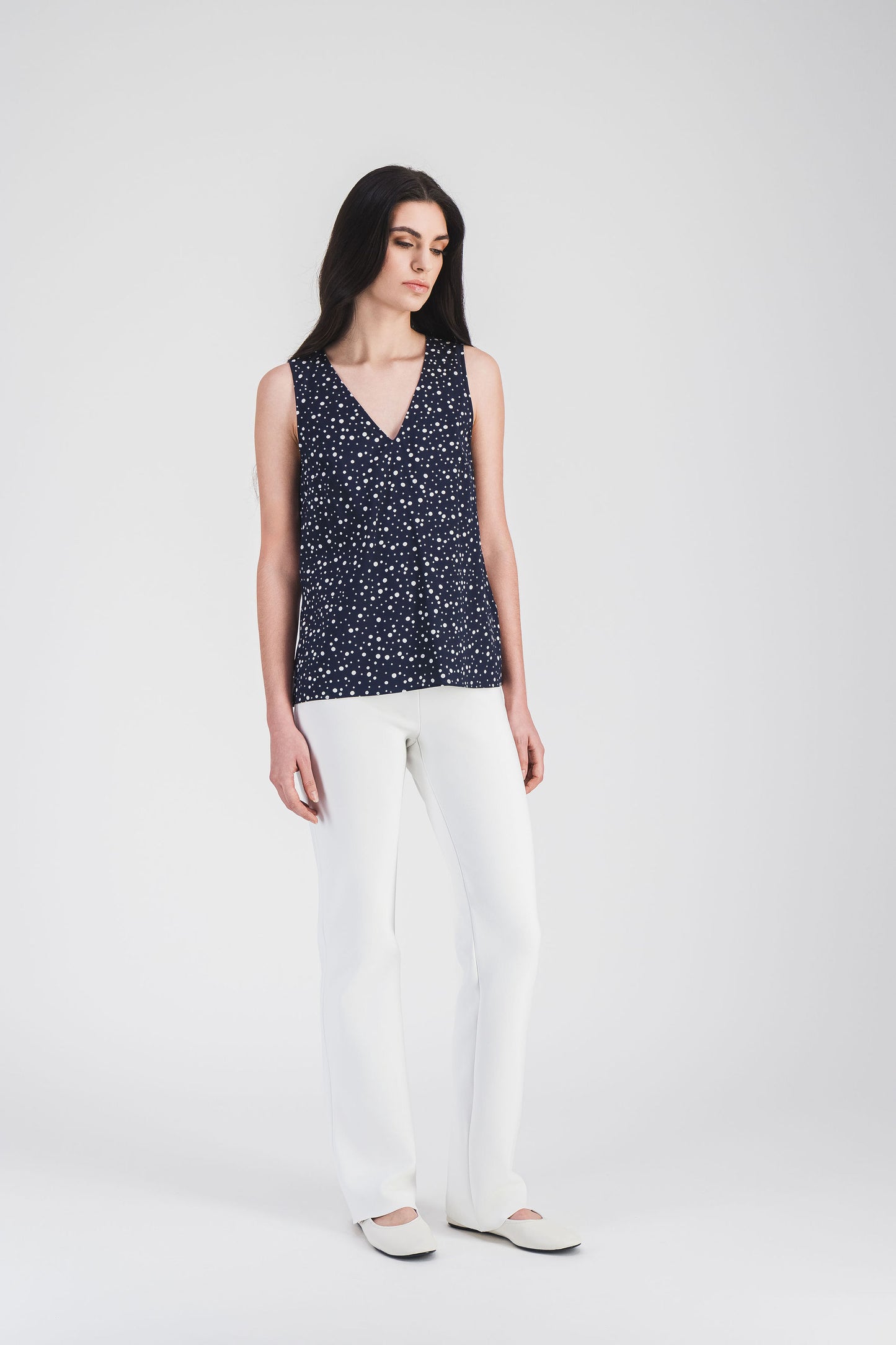Haut fluide en soie mélangée marine avec pois délicats, coupe évasée et encolure en V, parfait pour un look estival chic.