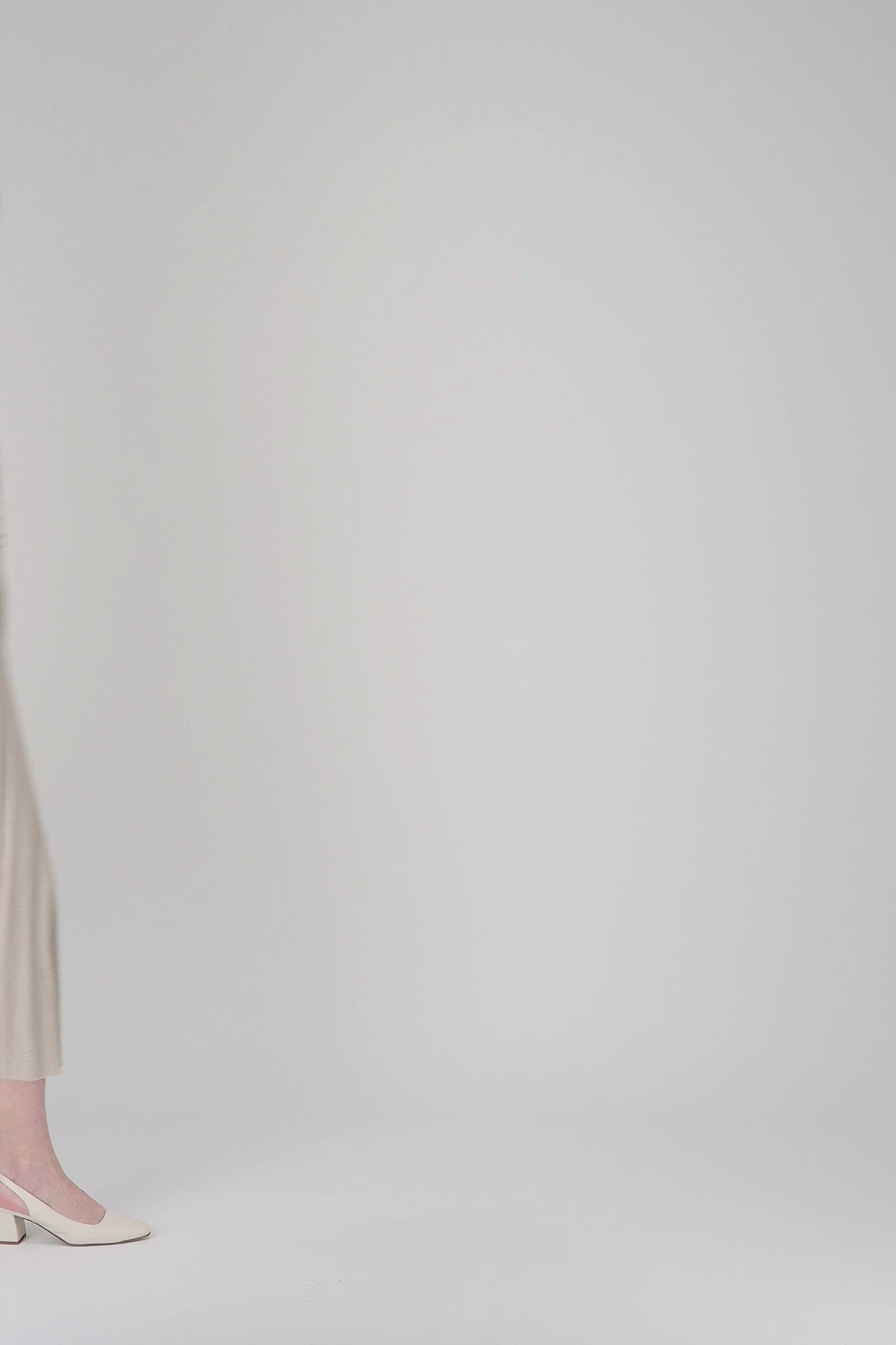 Cette robe longue cintrée avec col V, manches volantées et tissu scintillant offre une silhouette fluide et sophistiquée grâce au plissé soleil.
