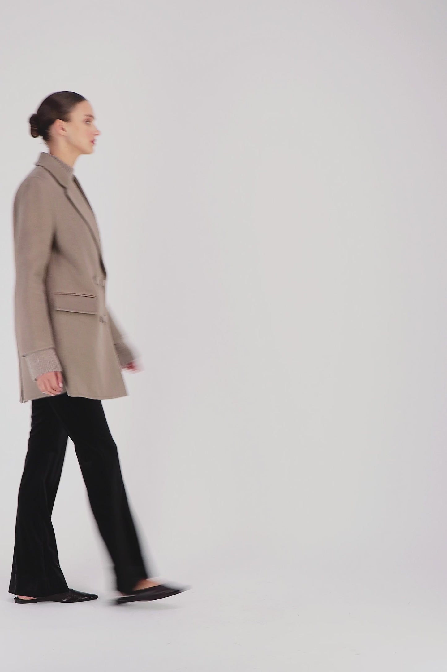 Vidéo d'un modèle portant un manteau mi-long taupe moyen orné d'une coupe droite, un grand col tailleur, un boutonnage croisé et des poches à rabat.