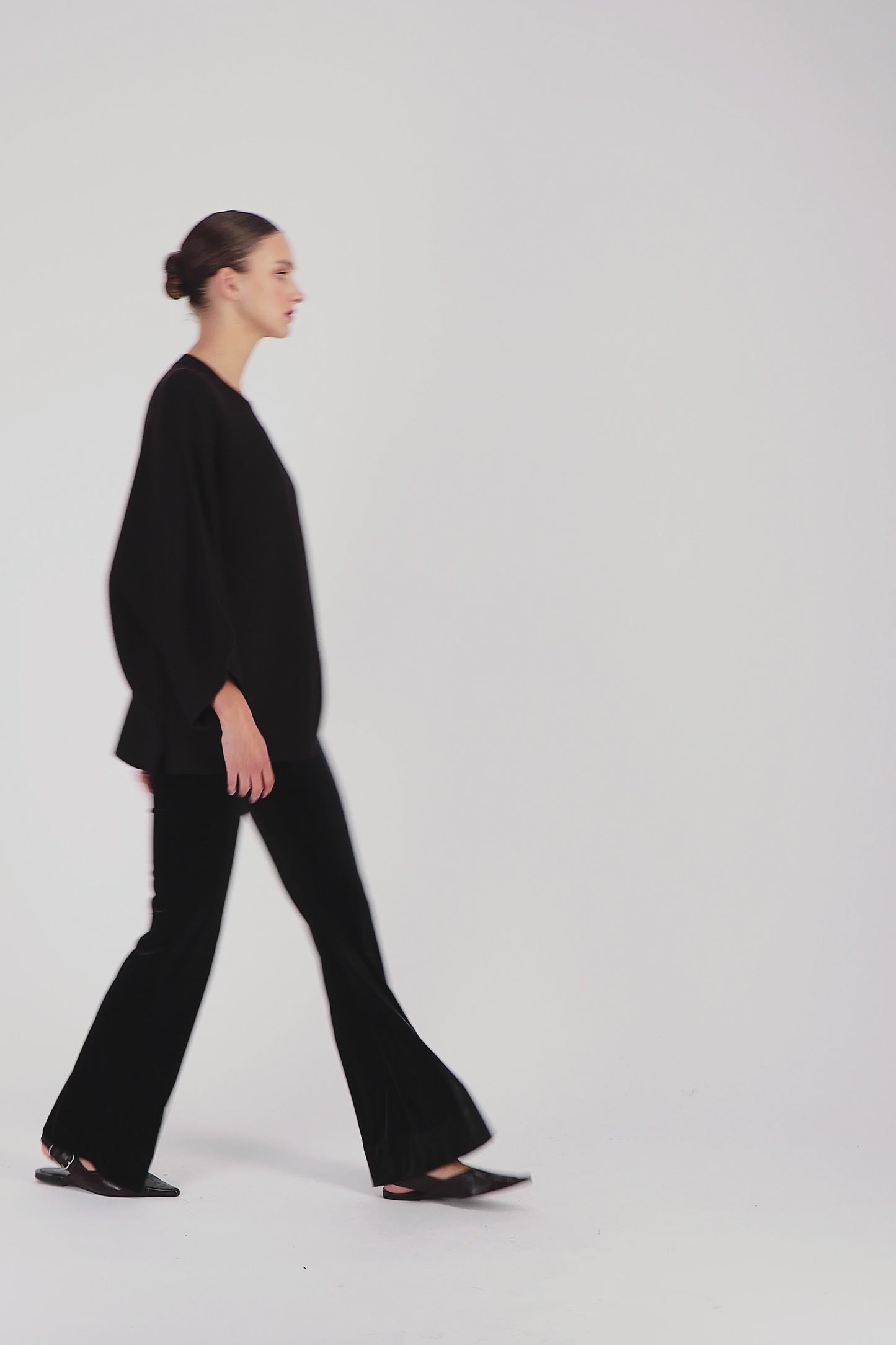 Vidéo d'une modèle portant un pantalon en velours ebene orné d'une coupe ample, zip latérale invisible et des jambes évasées.