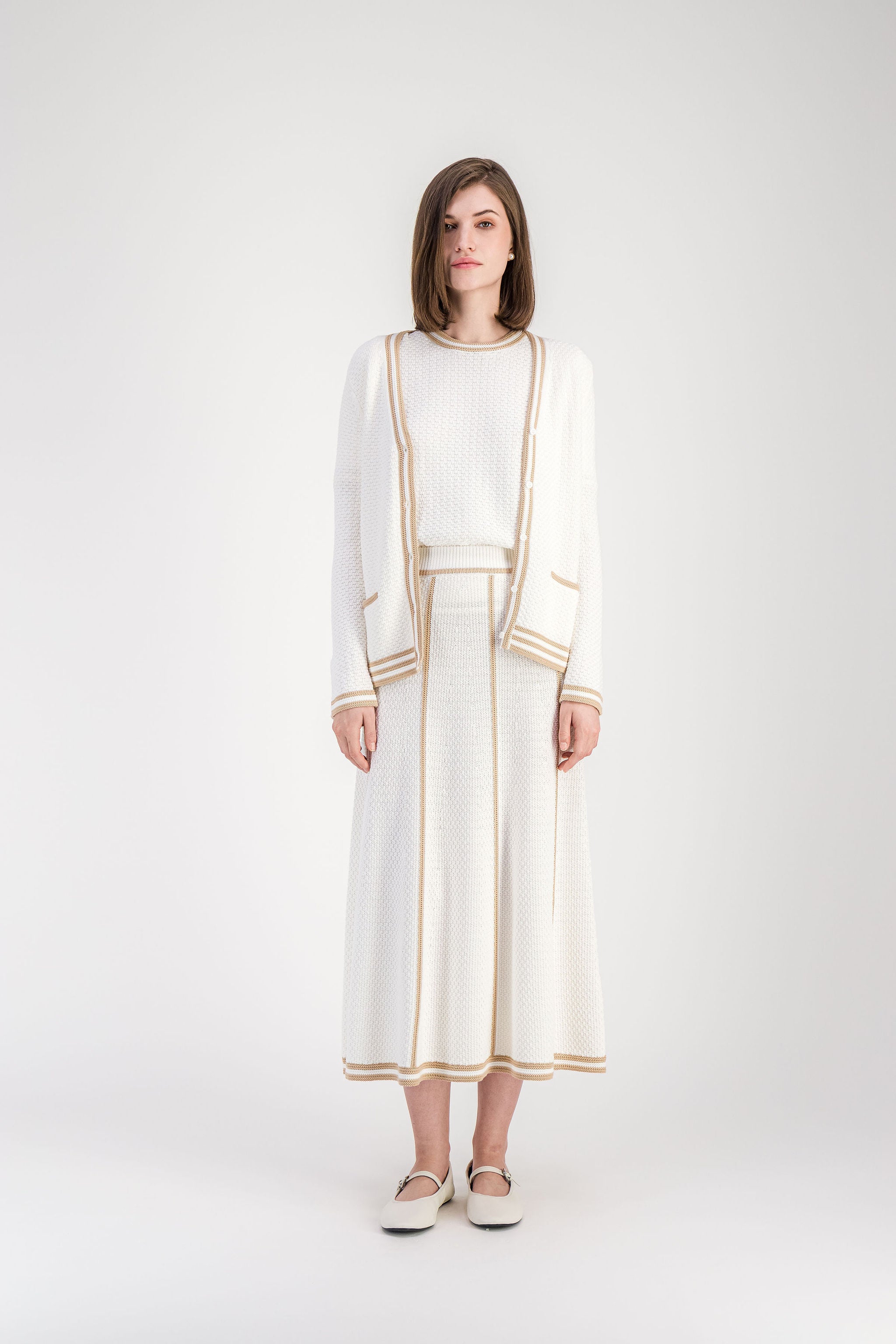 Cardigan beige moyen en maille structurée avec poches passepoilées et finitions rayées.