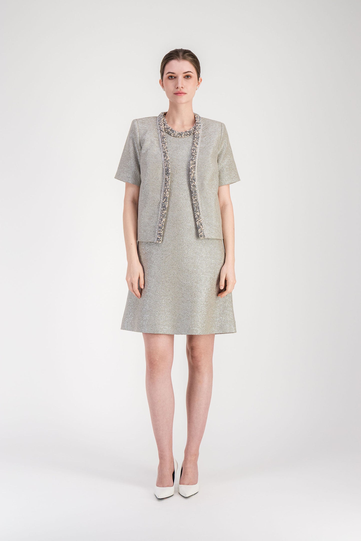 Robe en jersey lamé lumineux, silhouette droite et encolure ronde ornée d’un travail brodé délicat.