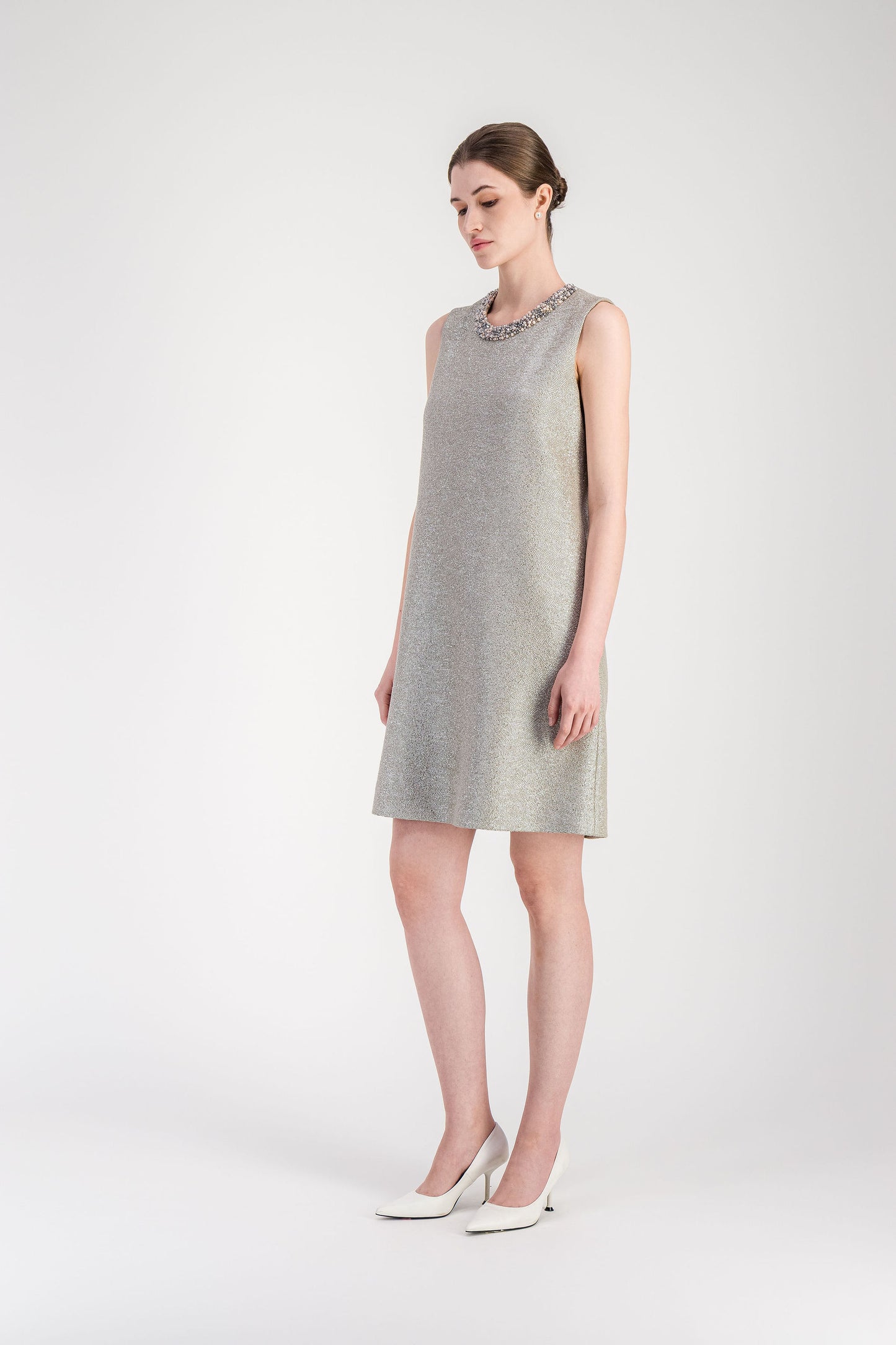 Détail du col rond brodé sur robe droite en jersey lamé argent à effet lumineux.