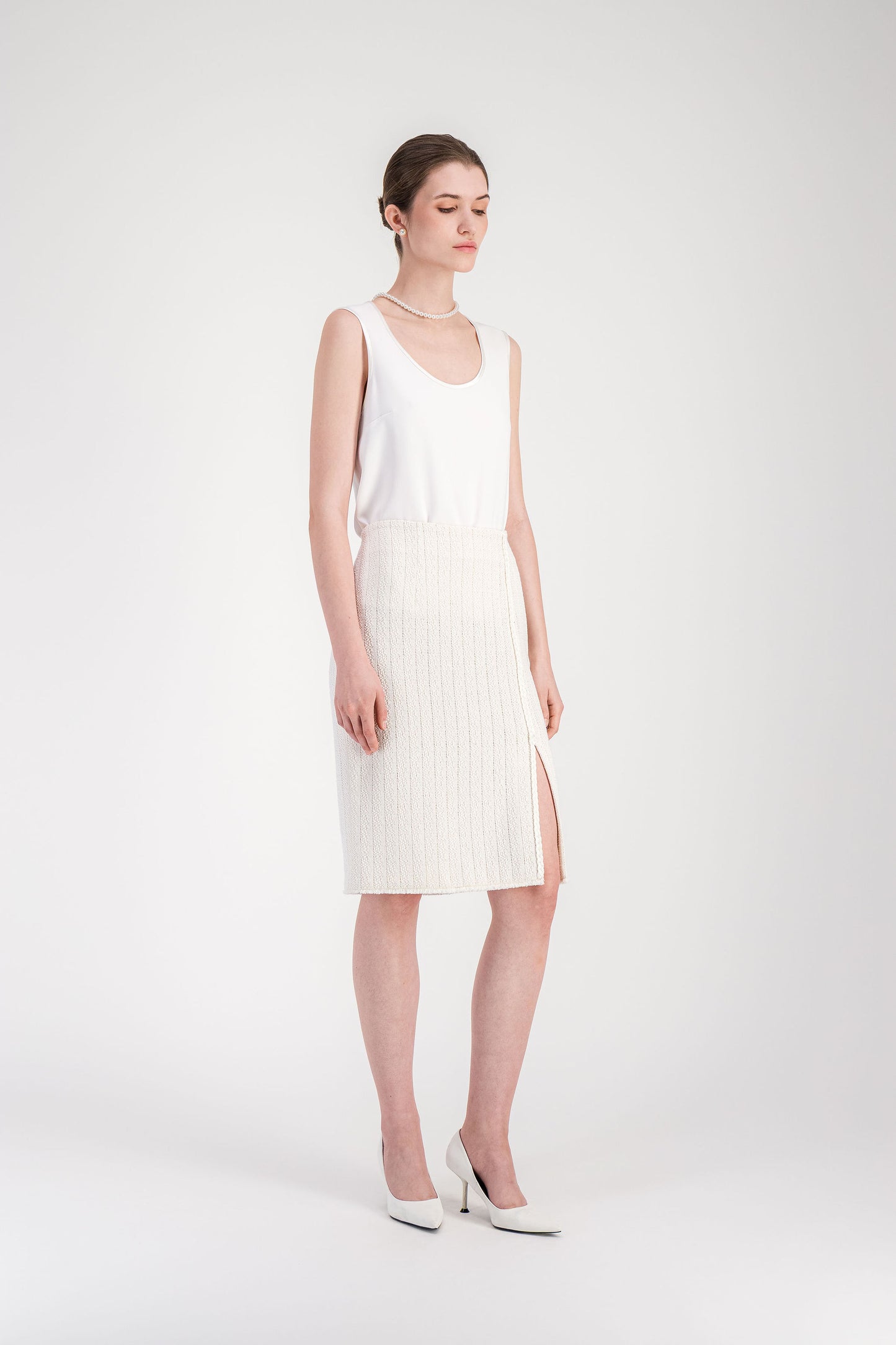 Jupe élégante blanc cassé en tweed avec galon tressé vertical et taille droite.