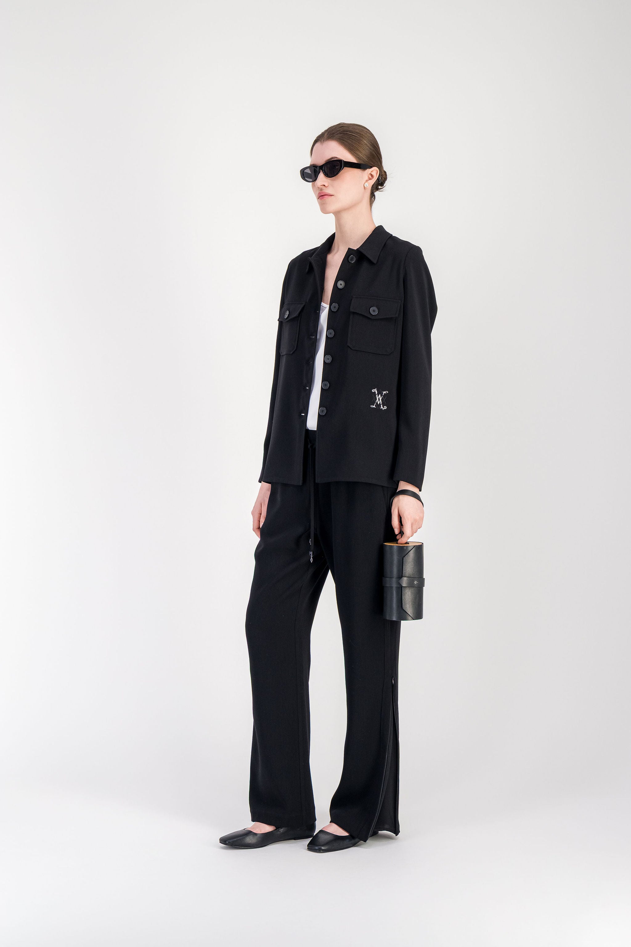 Chemise noire à manches longues avec poches carrées et broderie discrète du logo.