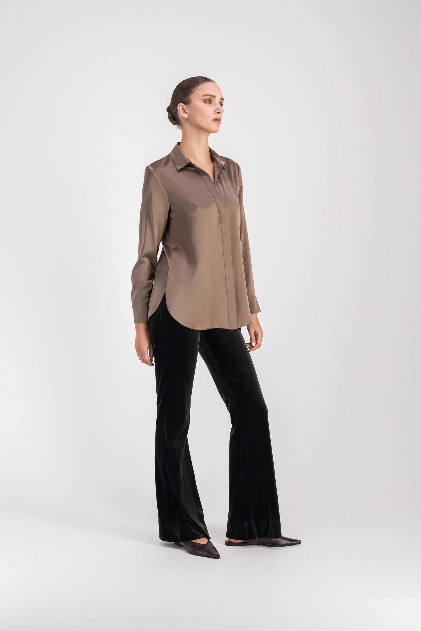 Modèle en position 3/4 portant une chemise en soie taupe moyen dotée d'une patte de boutonnage cachée, d'un col chemise et de boutons nacrés aux poignets.