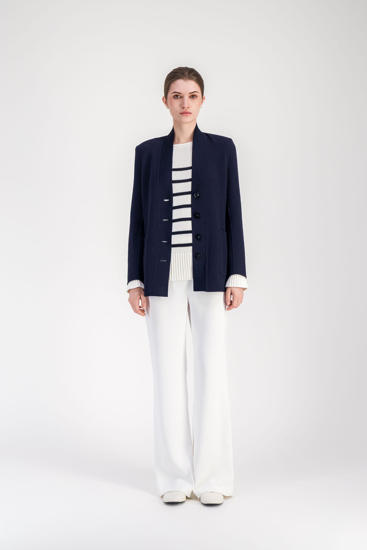 Cardigan droit en laine marine 100% avec col châle en V profond, fermeture centrée à cinq boutons et poches plaquées.