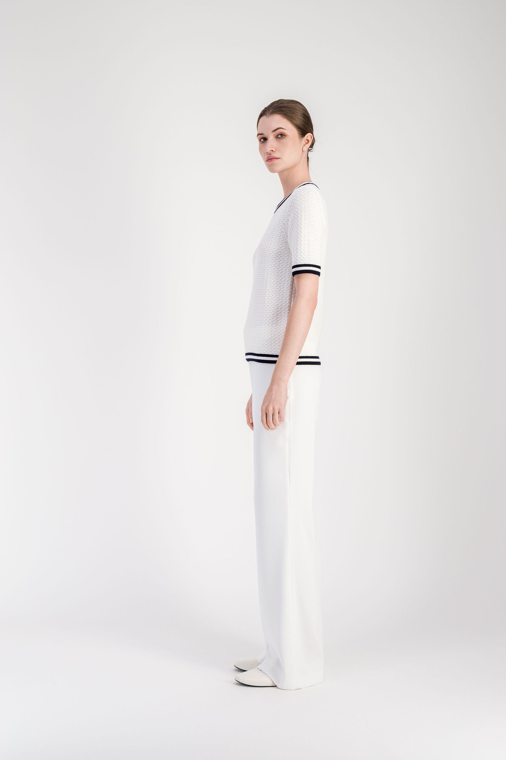 Pull manches courtes blanc avec col rond et bordures rayées noires.