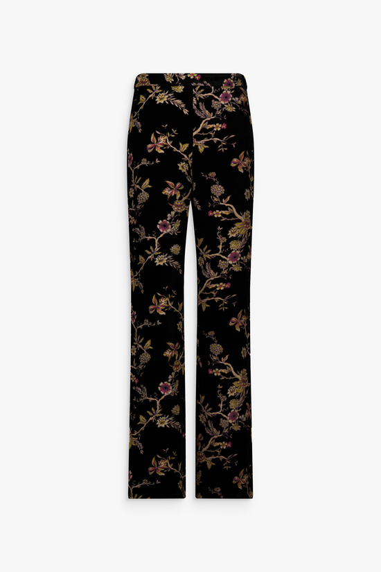 Pantalon en velours de soie noir à motifs floraux porté.