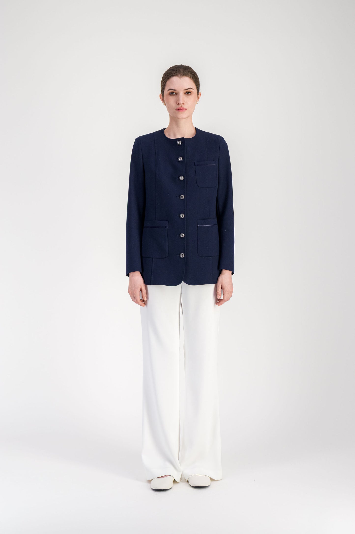 Veste femme bleu marine structurée avec découpes verticales et fermeture boutonnée.