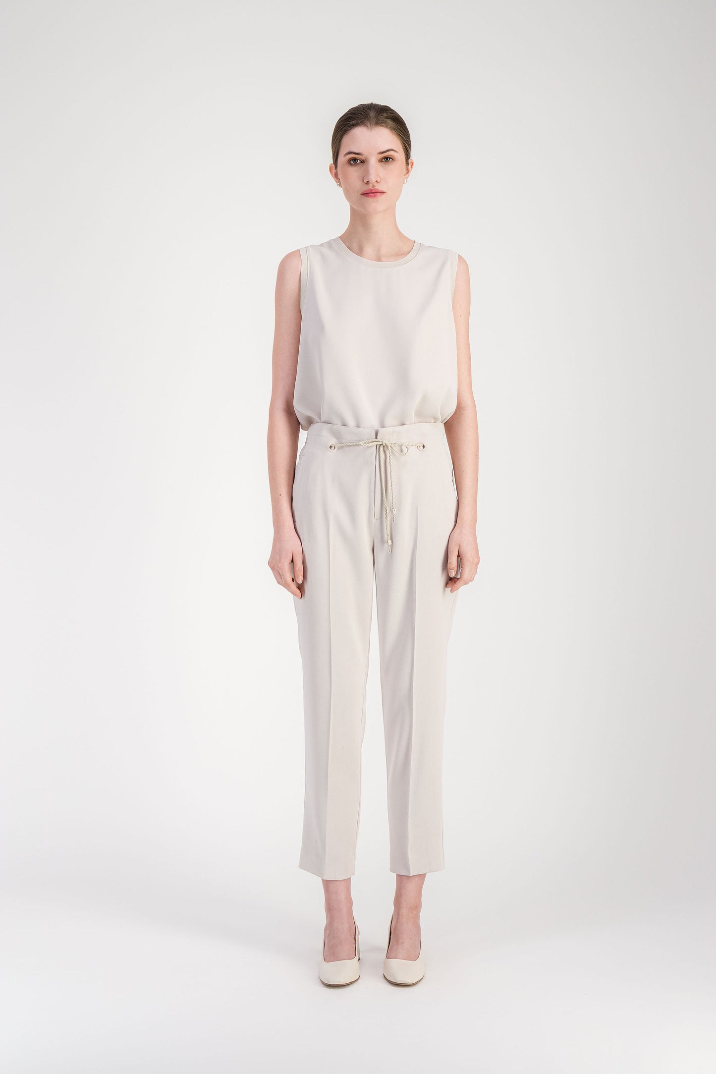 Pantalon fuselé beige à la ligne structurée avec taille ajustable par cordon.