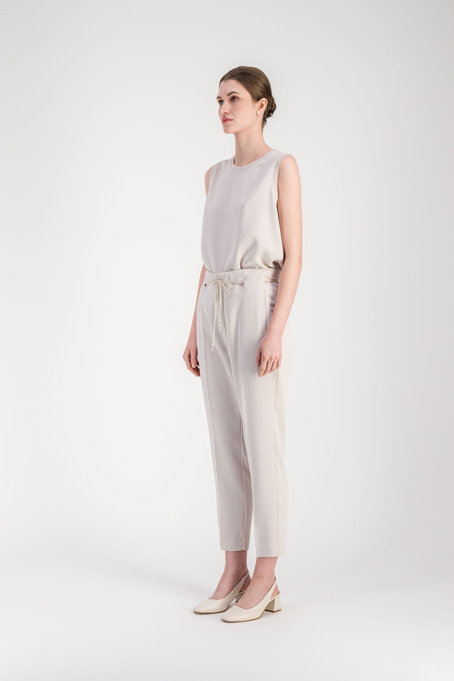 Pantalon beige coupe fuselée avec poches latérales et ligne nette le long de la jambe.