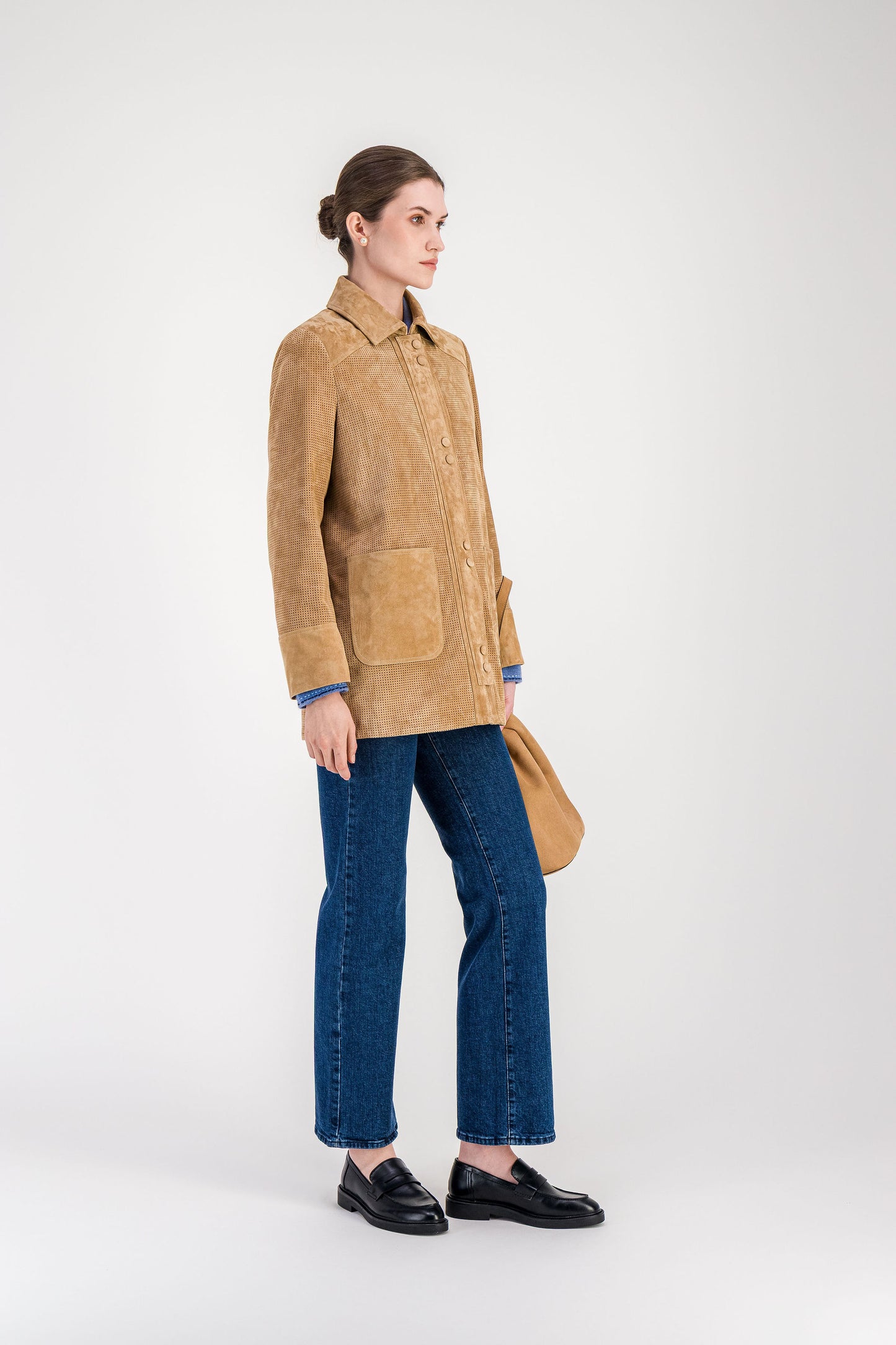 Veste en daim beige perforé portée avec pantalon assorti pour une silhouette élégante.