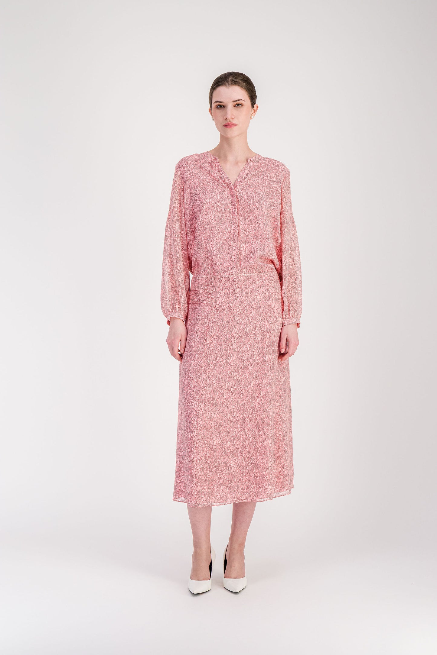 Blouse fluide rose pâle avec encolure ronde et manches ballon.