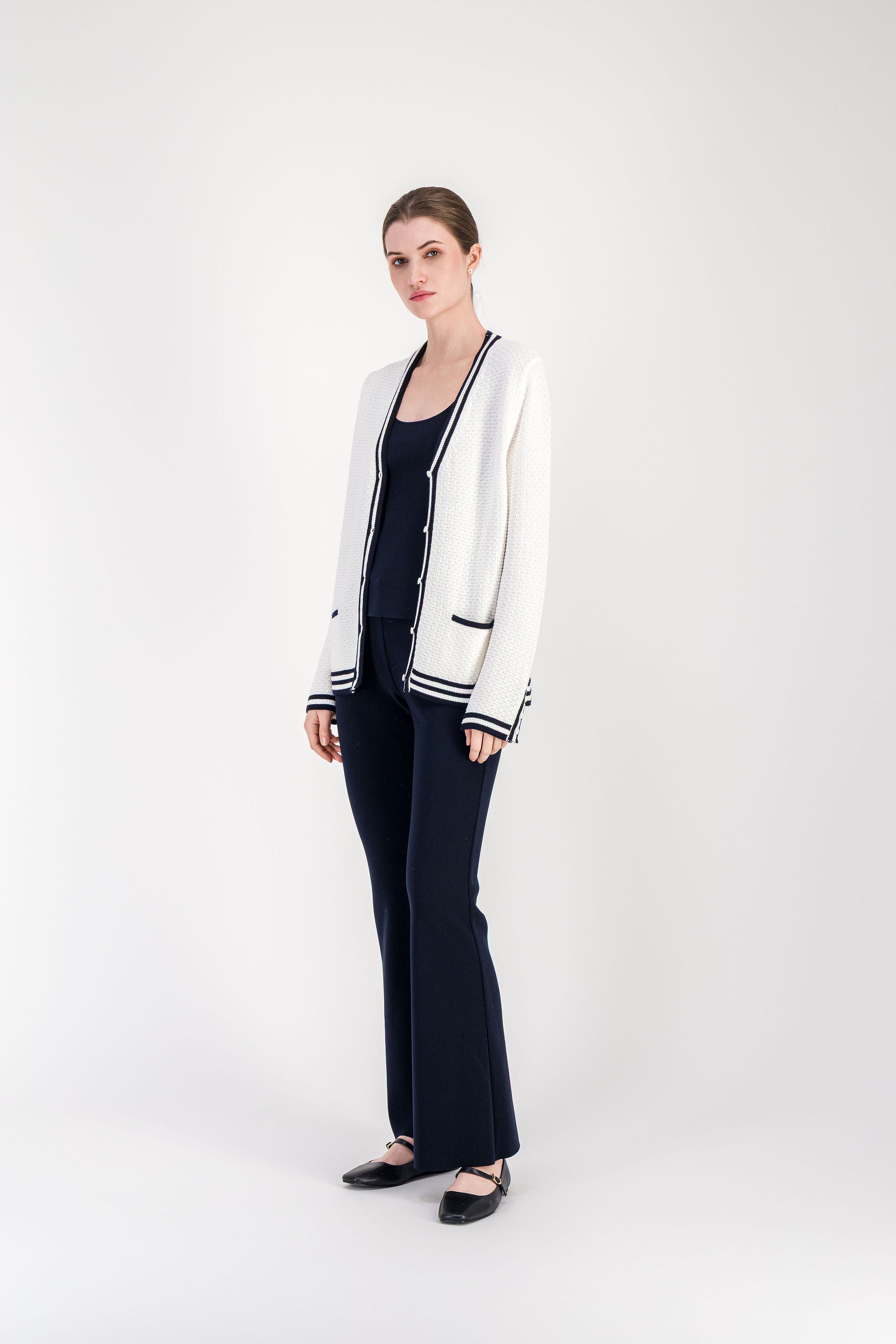 Cardigan en maille texturée blanc cassé avec poches passepoilées et fermeture boutonnée.