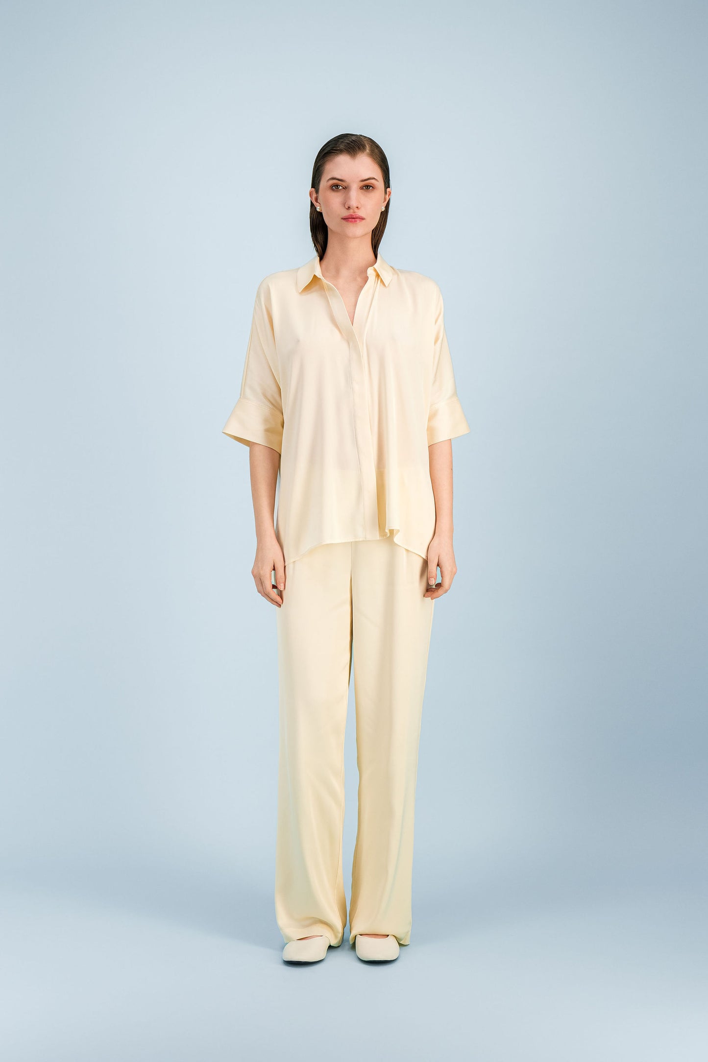 Pantalon en soie jaune clair coupe droite avec côté élastiqué discret.