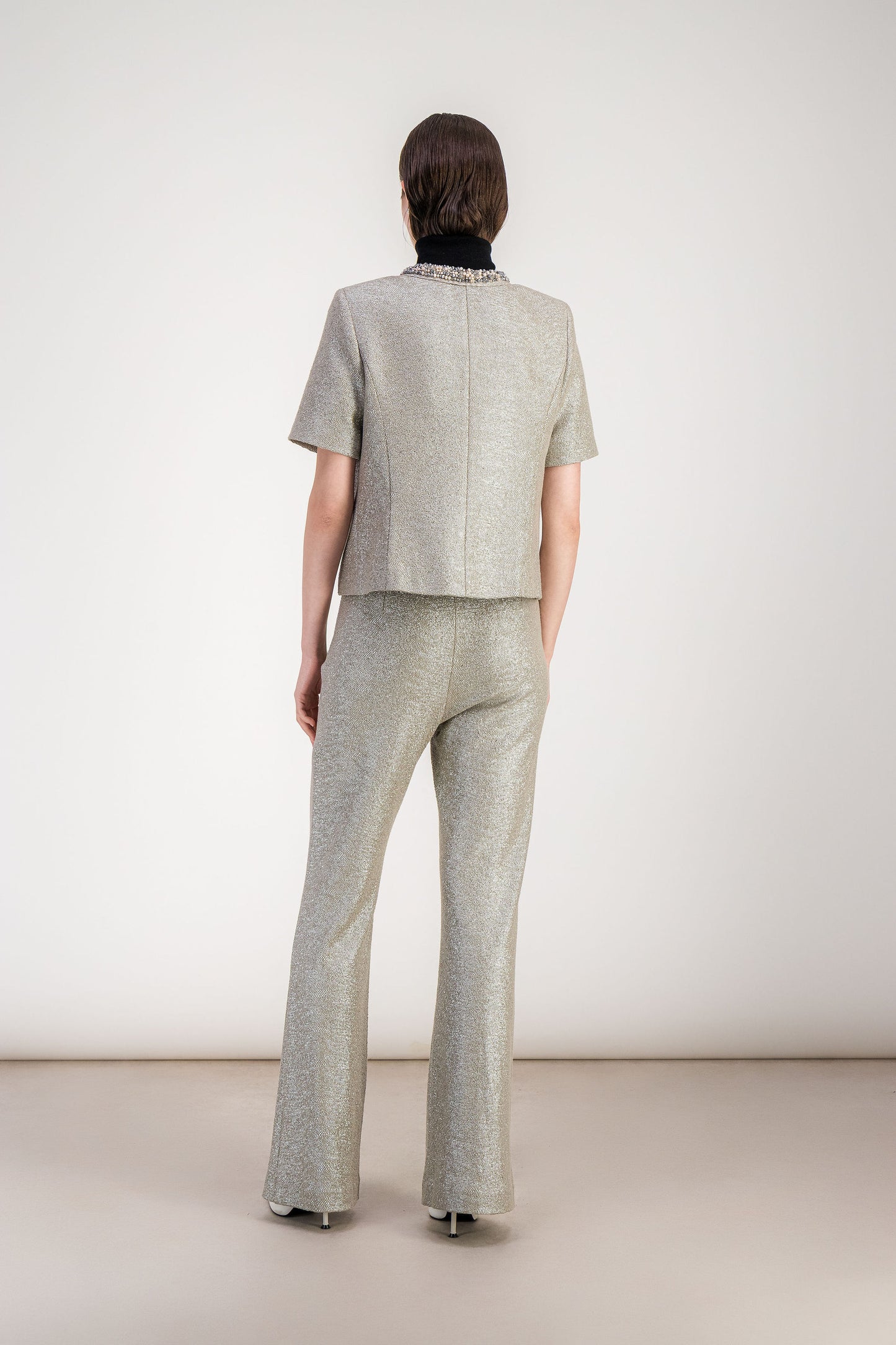 Finition brodée précieuse sur veste droite en jersey lamé argent.