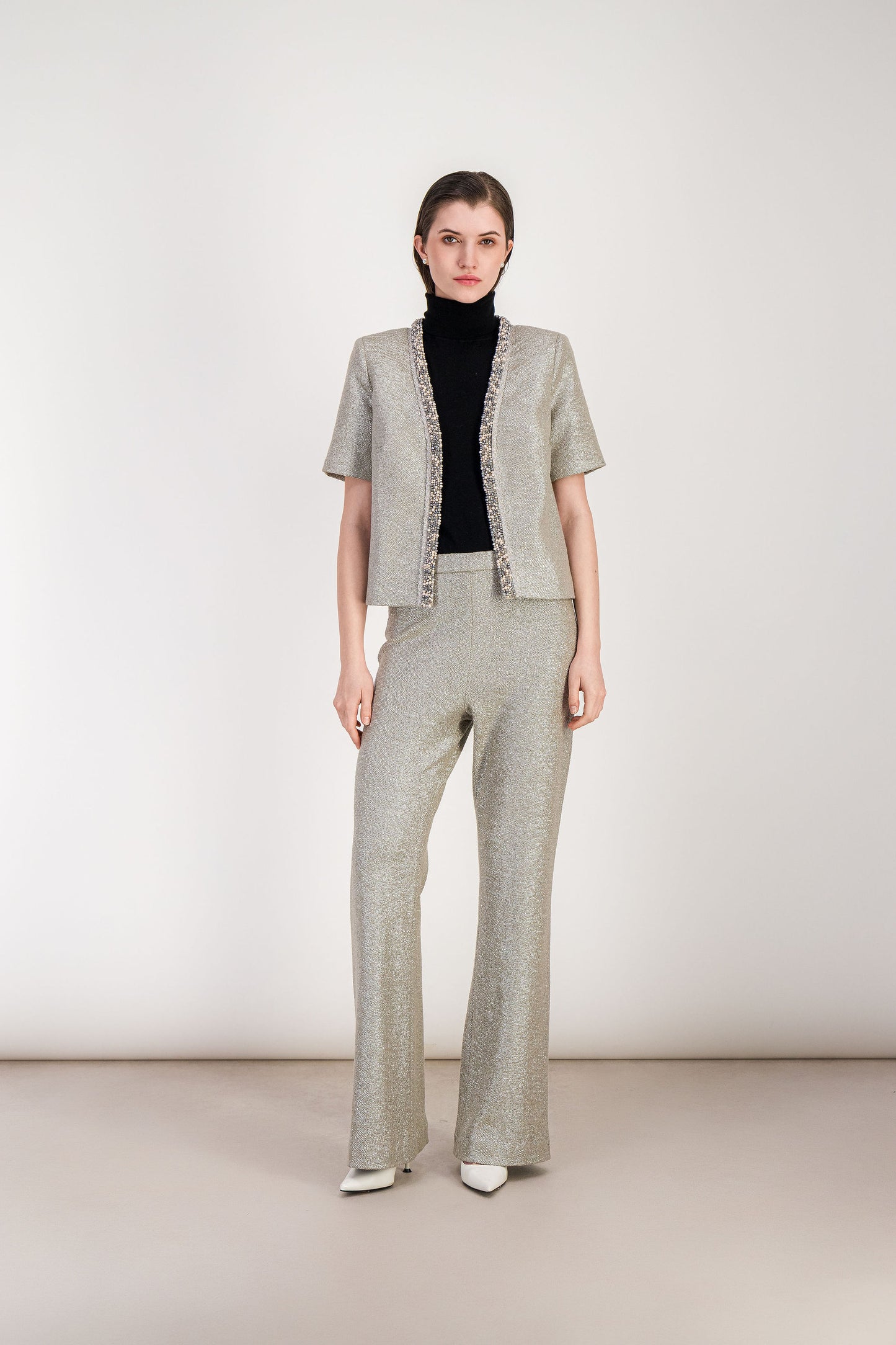 Pantalon lamé argent à la matière lumineuse et à la ligne droite légèrement évasée.